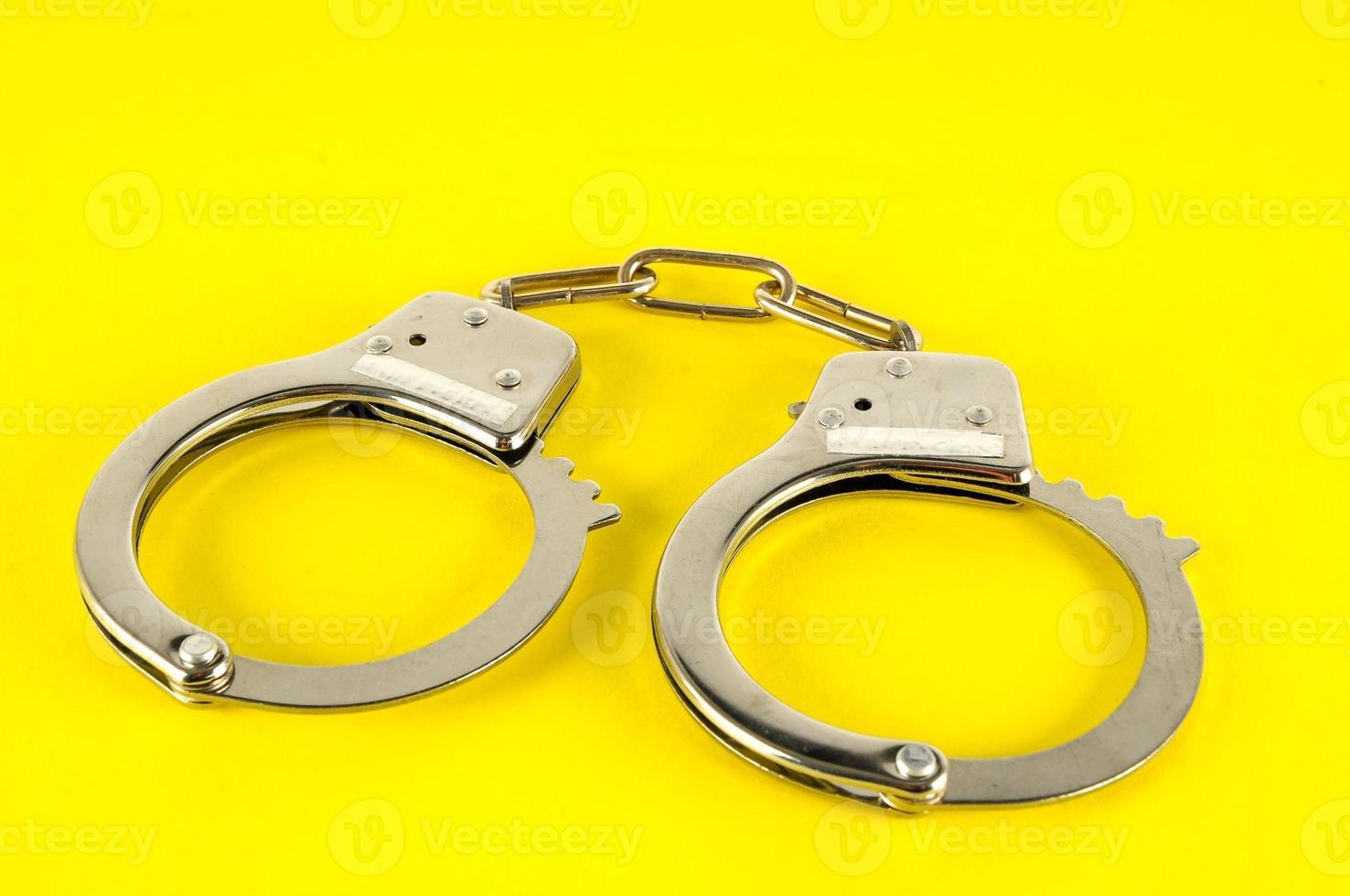 Metal handcuff on yellow background photo