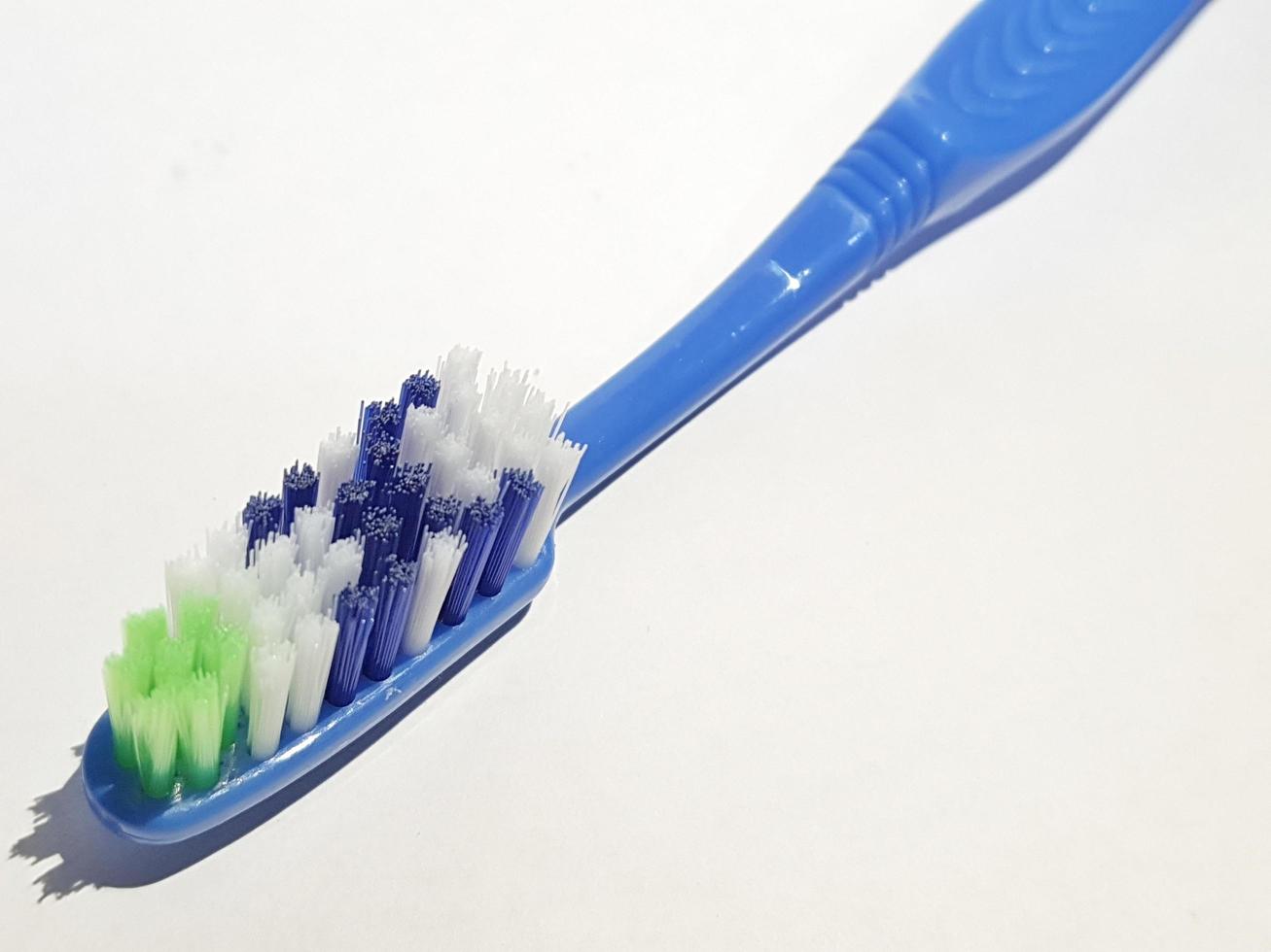 Isolated white photo of a plastic toothbrush that has been used several times. This toothbrush has a blue handle.