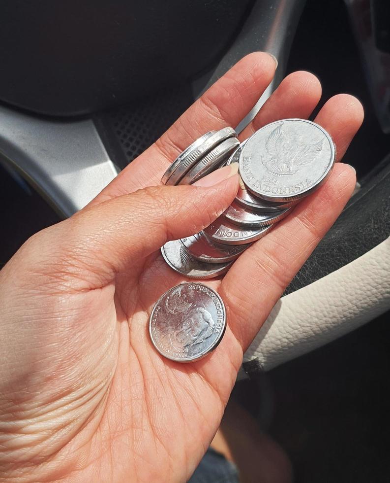 una mano sostiene varias monedas de rupias. estas monedas se suelen utilizar para dar a las manadas de personas que ayudan a cruzar el vehículo o les indican que den la vuelta. foto