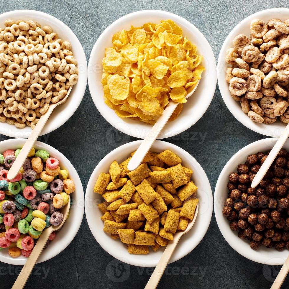 Variety of cold cereals in white bowls with spoons photo