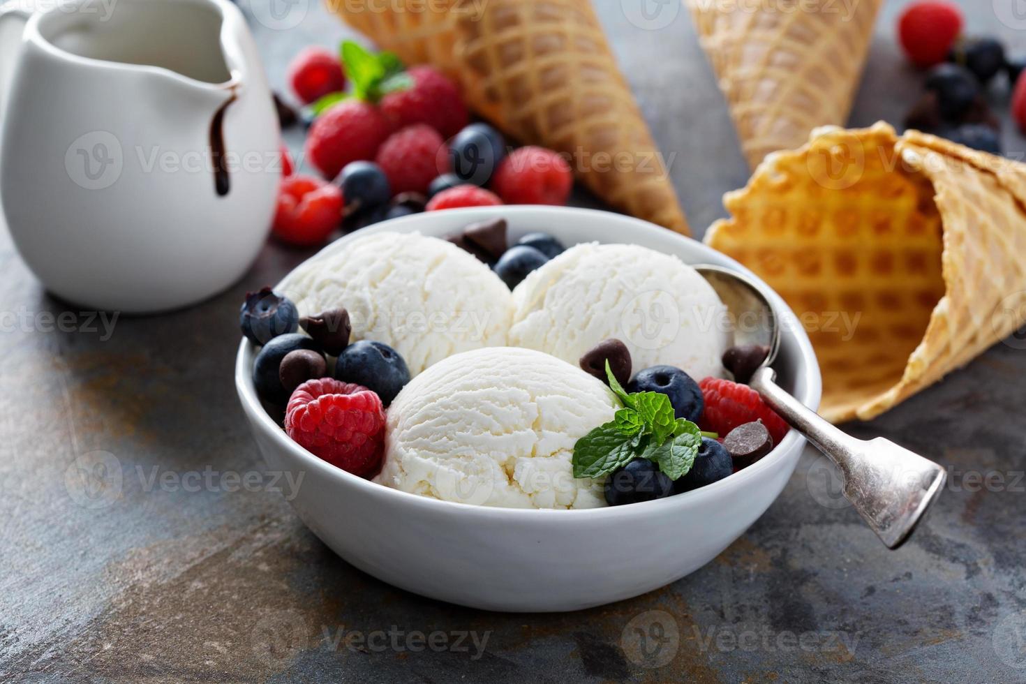 bolas de helado de vainilla en un bol con bayas frescas foto