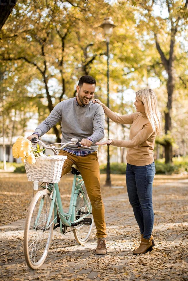 Active senior couple together enjoying romantic walk with bicycle in golden autumn park photo