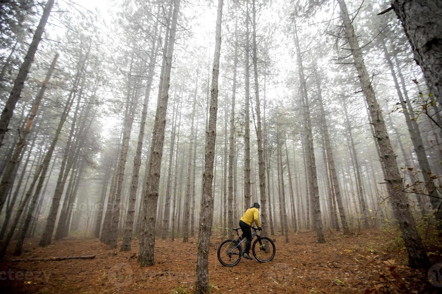 Young man biking through autumn forest photo