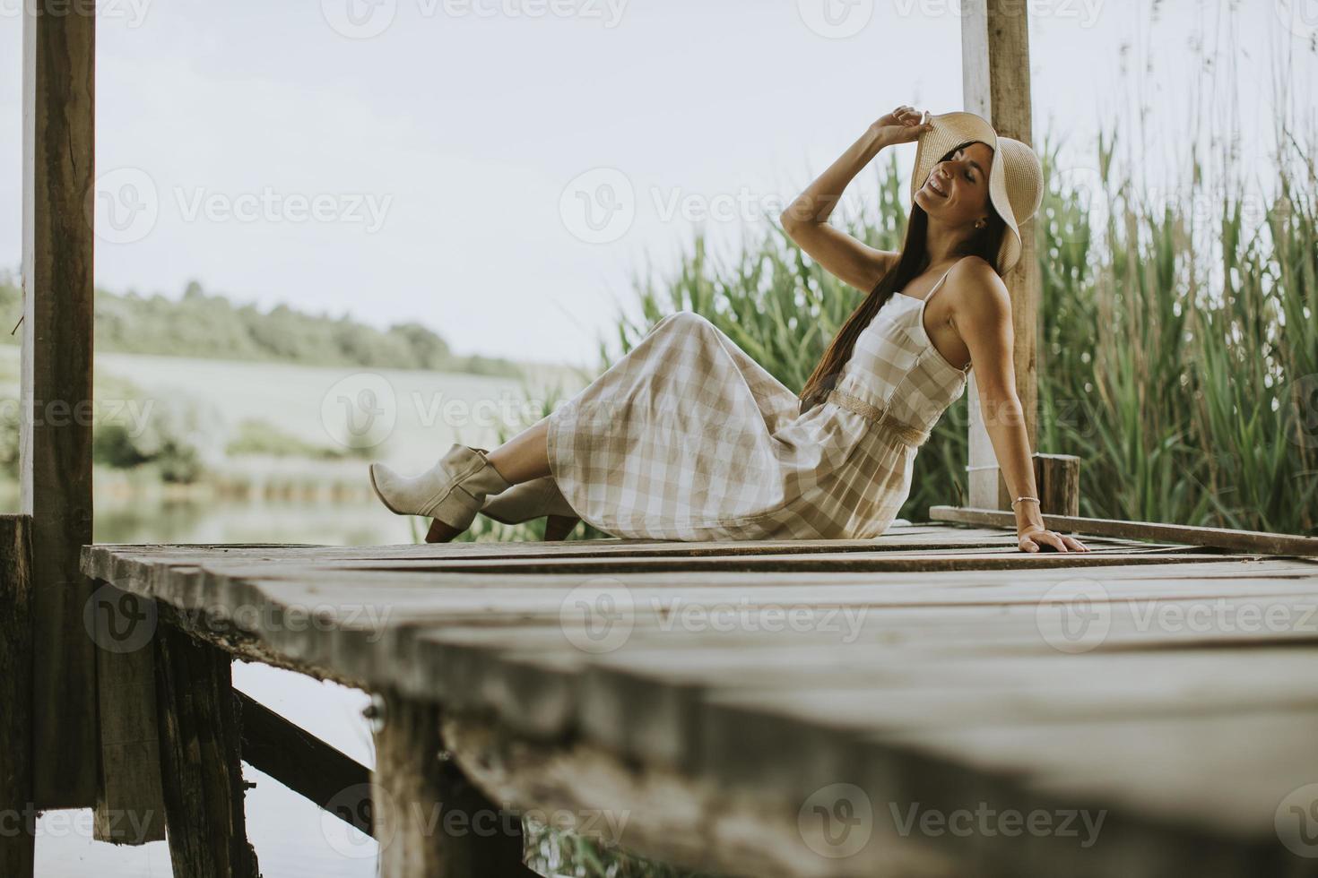 Relaxing young woman on wooden pier at the lake photo