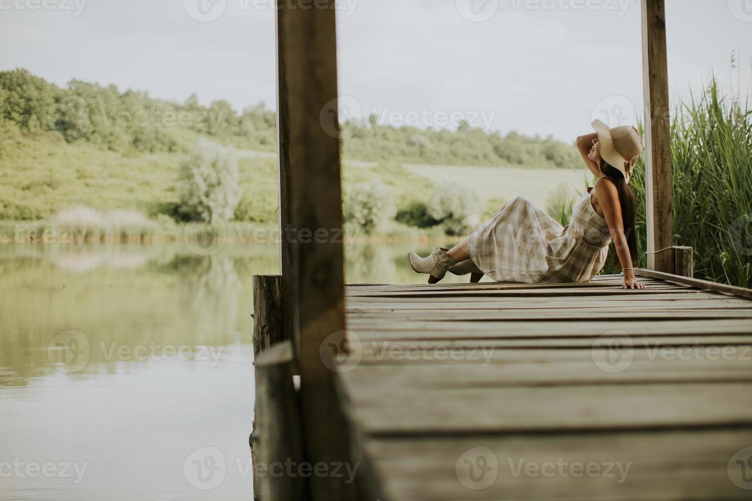 mujer joven relajante en el muelle de madera en el lago foto