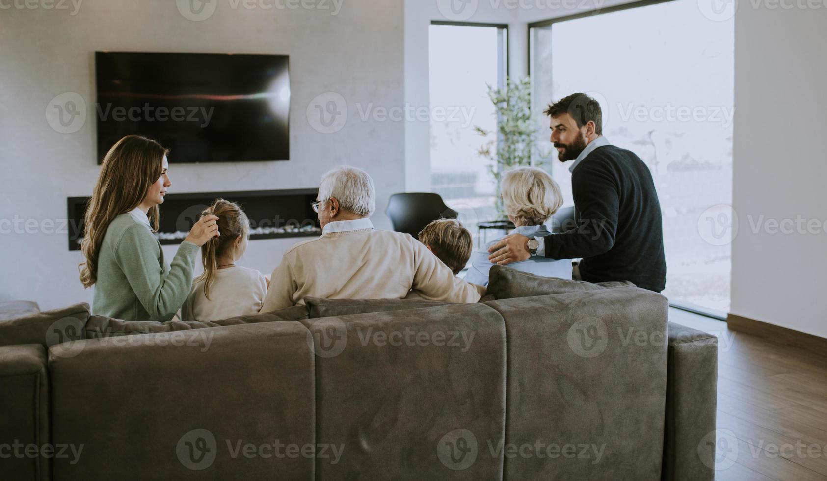 Multi generation family sitting together on the sofa at home and watching TV photo