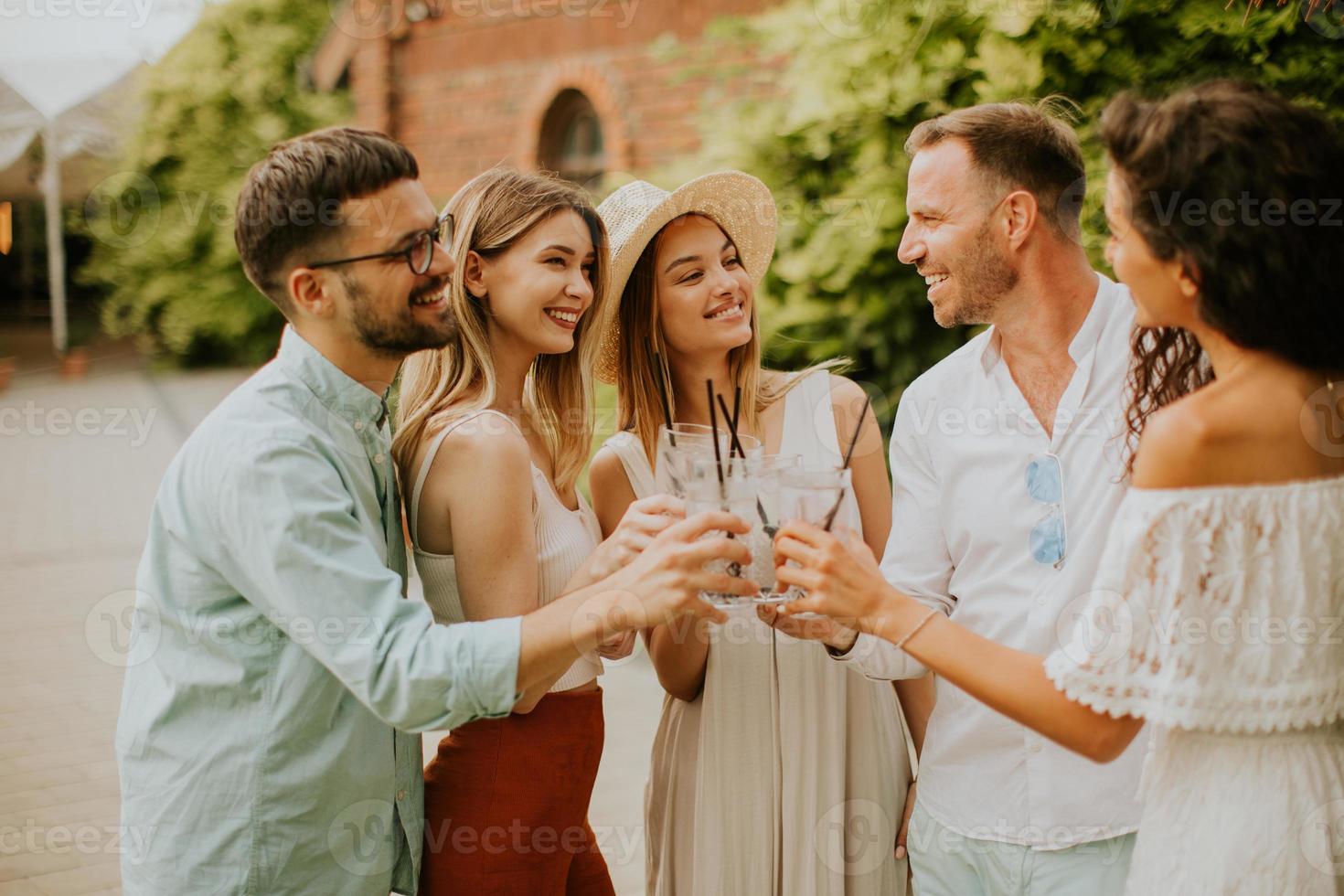 Group of happy young people cheering with fresh lemonade in the garden photo