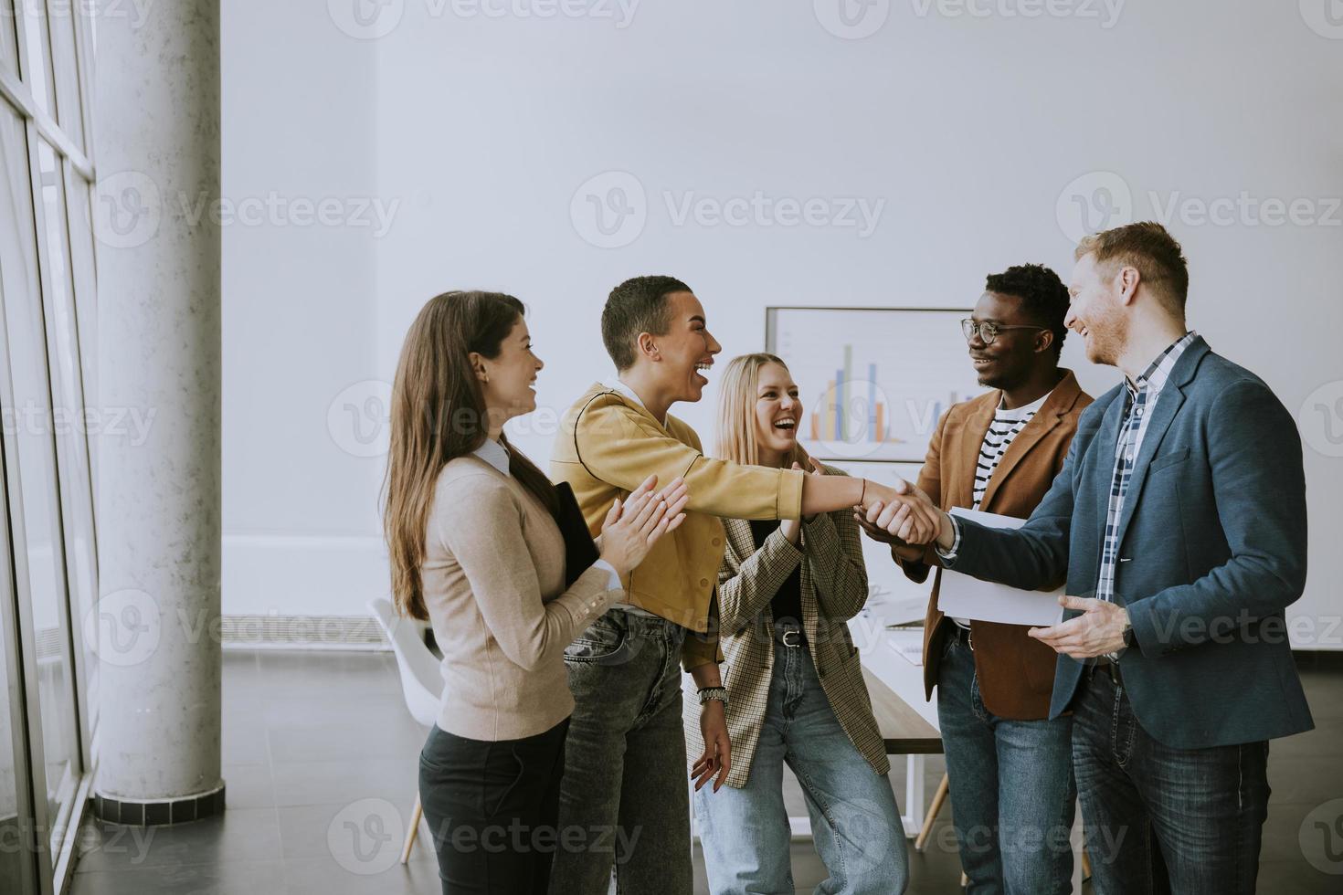 Memembers of creative team shaking hands while working in the modern office photo