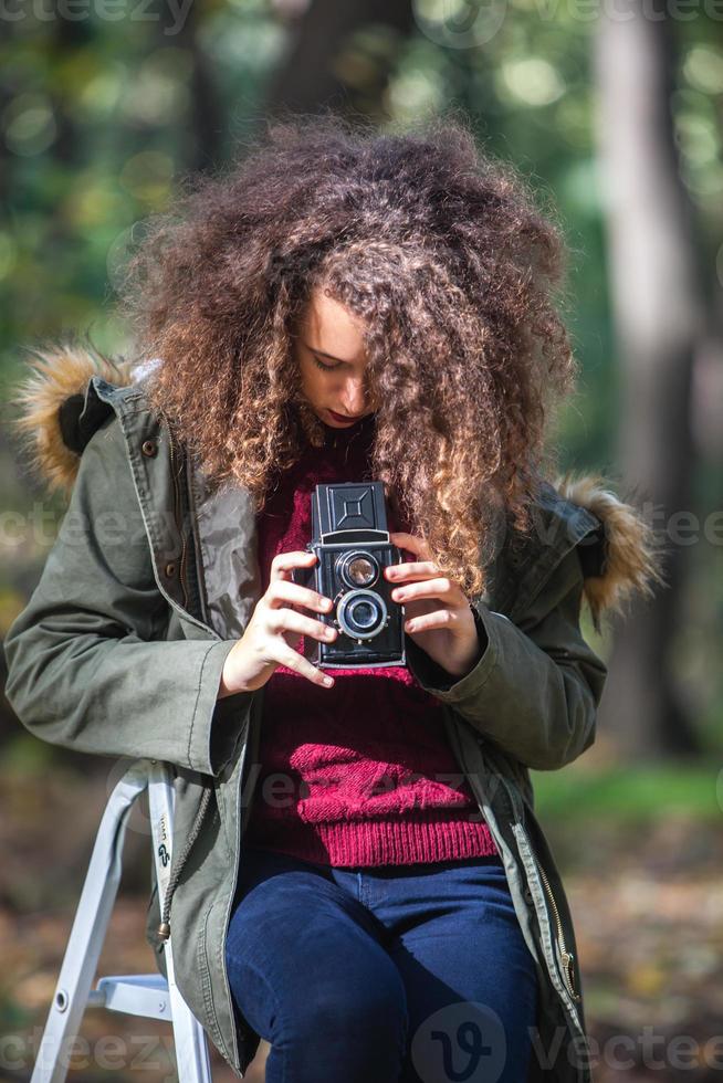 Teen girl with retro camera taking photos in nature