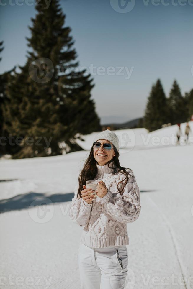 Young woman drinking lemonade  on the mountain ski track photo