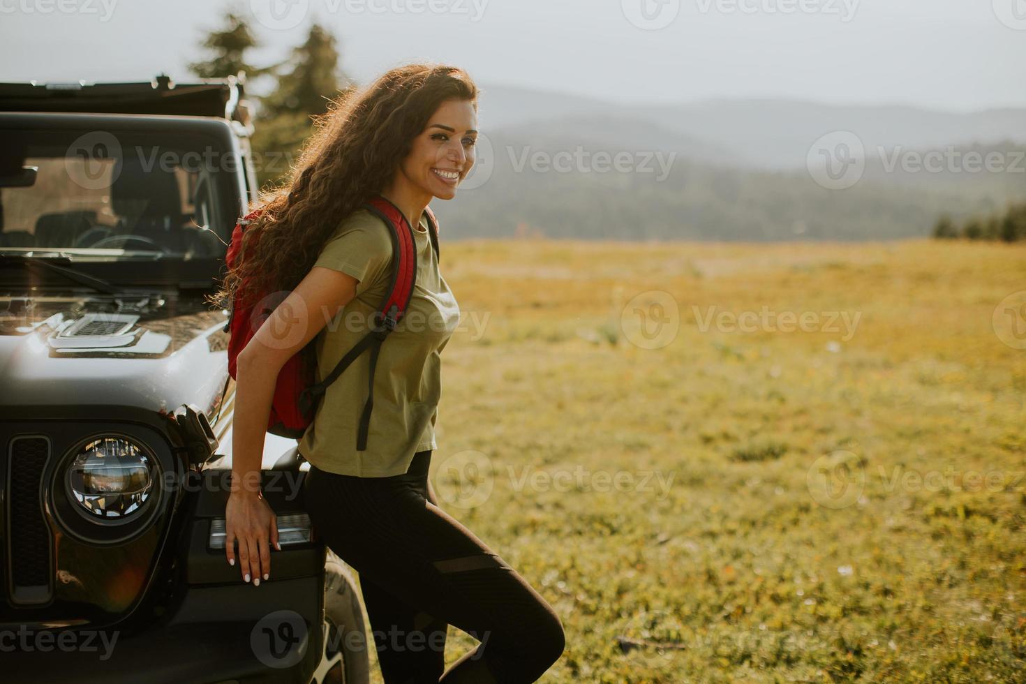 Young woman relaxing on a terrain vehicle hood at countryside photo