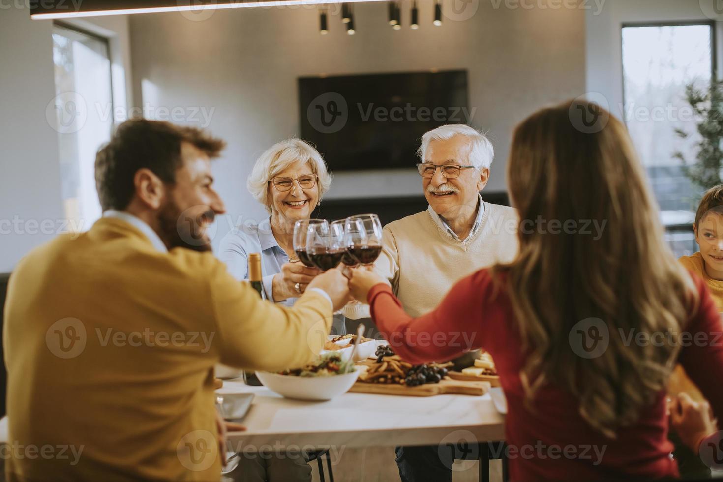 familia feliz cenando con vino tinto en casa foto