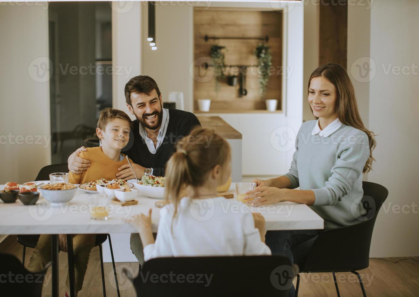 Young happy family talking while having lunch at dining table photo
