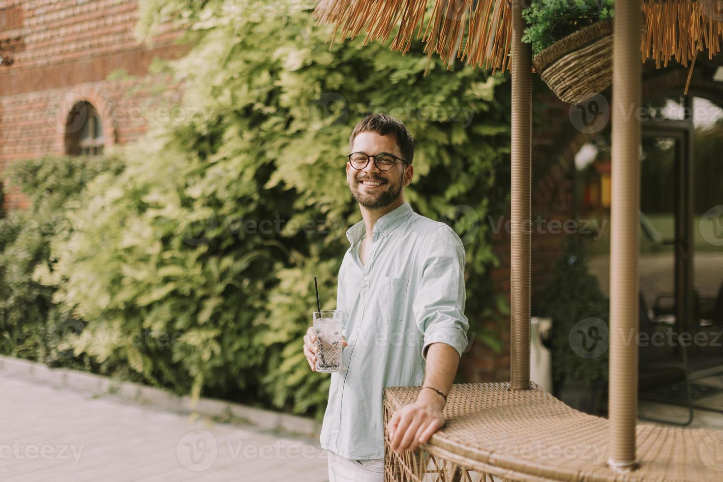 Young man drinking fresh cold lemonade at the pool bar photo