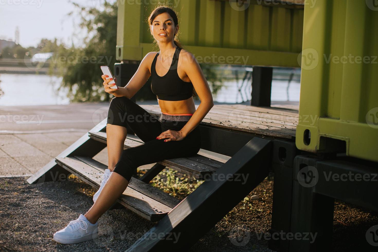 Pretty young woman  taking a break during exercising outside and using mobile phone photo