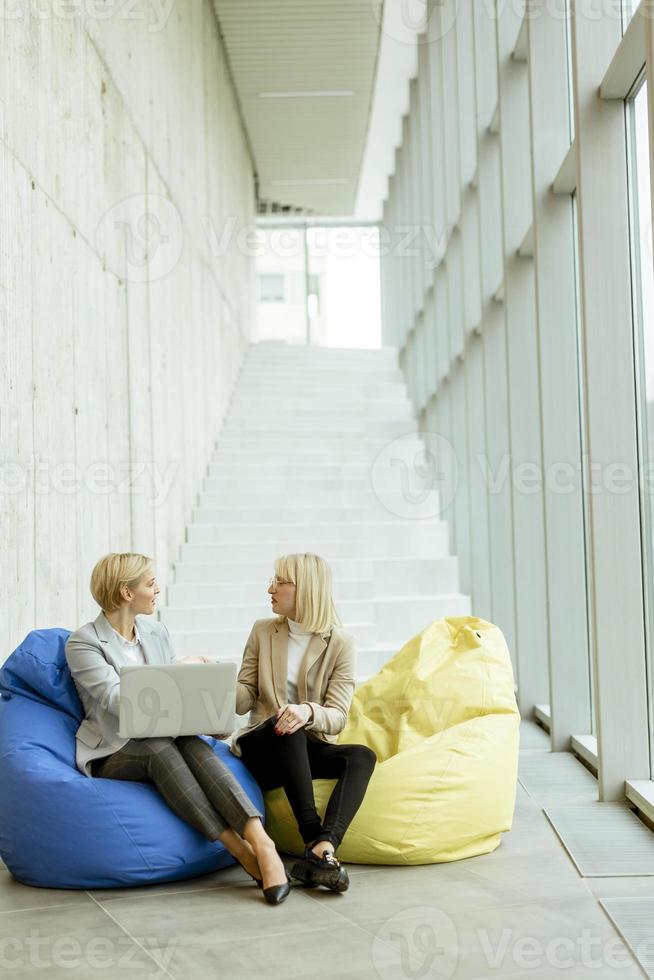 mujeres de negocios que usan computadoras portátiles en bolsas perezosas en la oficina moderna foto