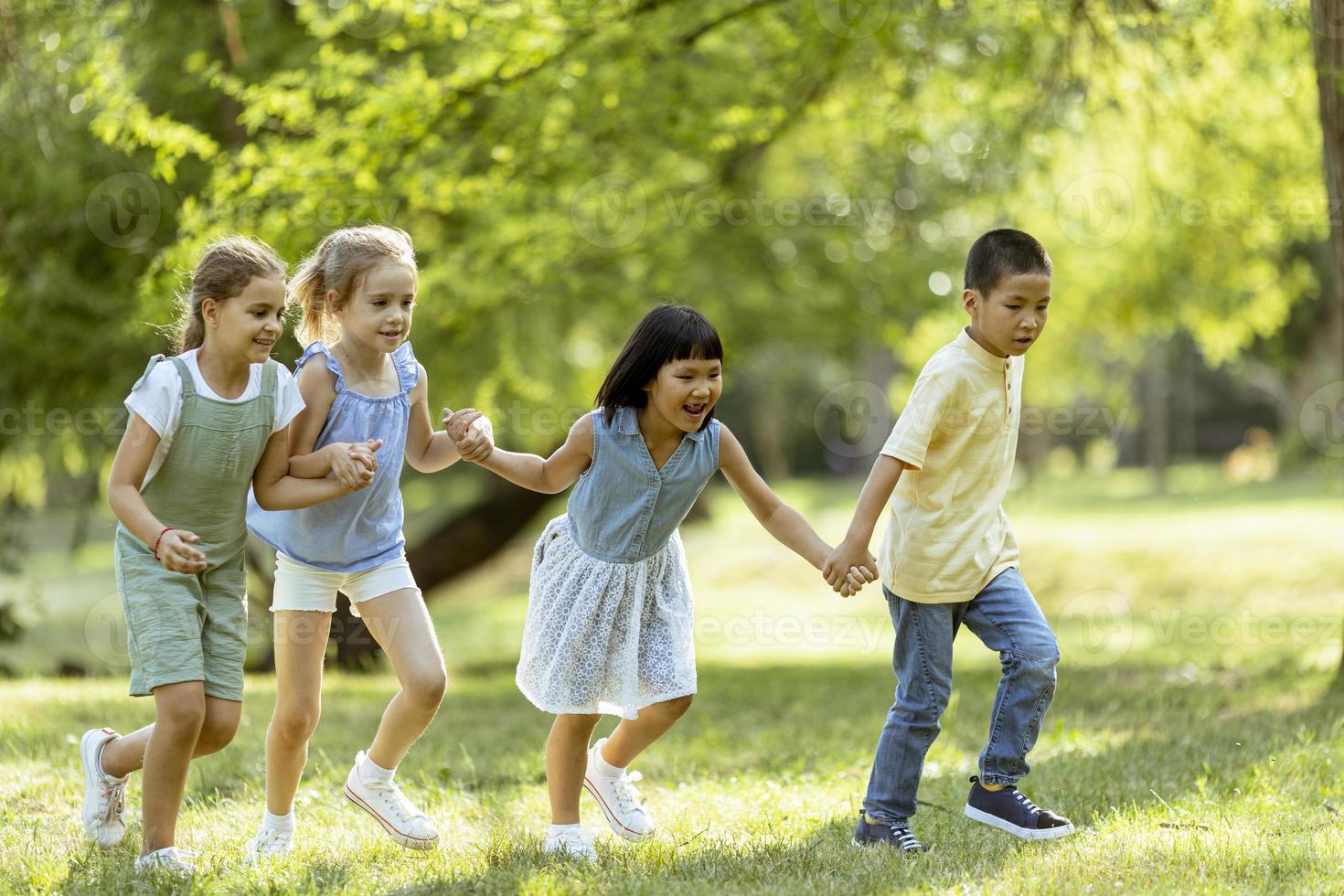 grupo de niños asiáticos y caucásicos divirtiéndose en el parque foto