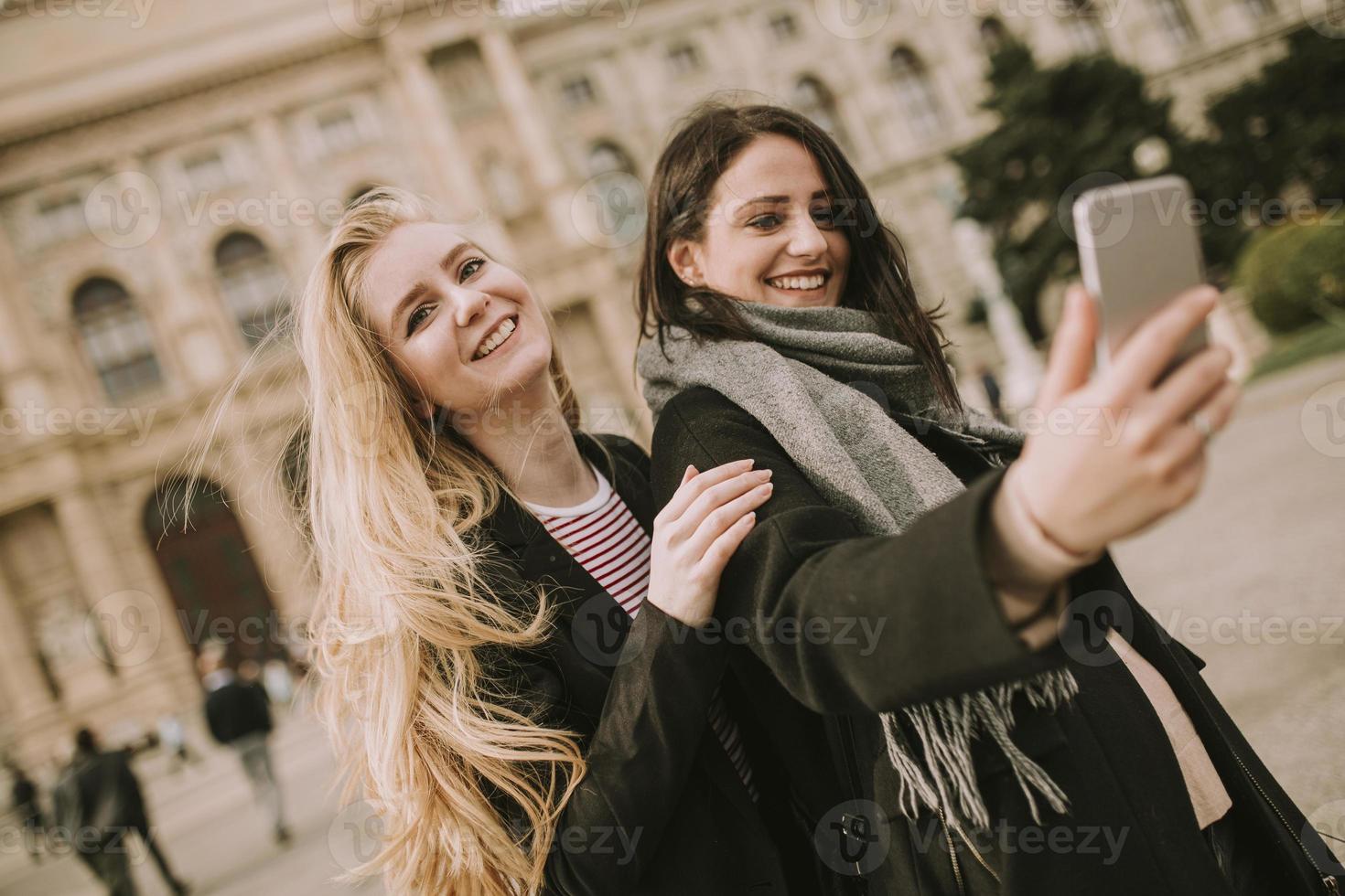 Young female tourists taking selfie with mobile photo in centre of Vienna, Austria