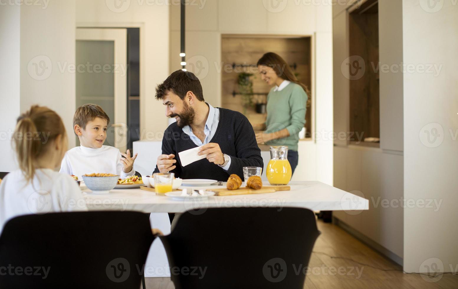 Young mother preparing breakfast for her family in the kitchen photo