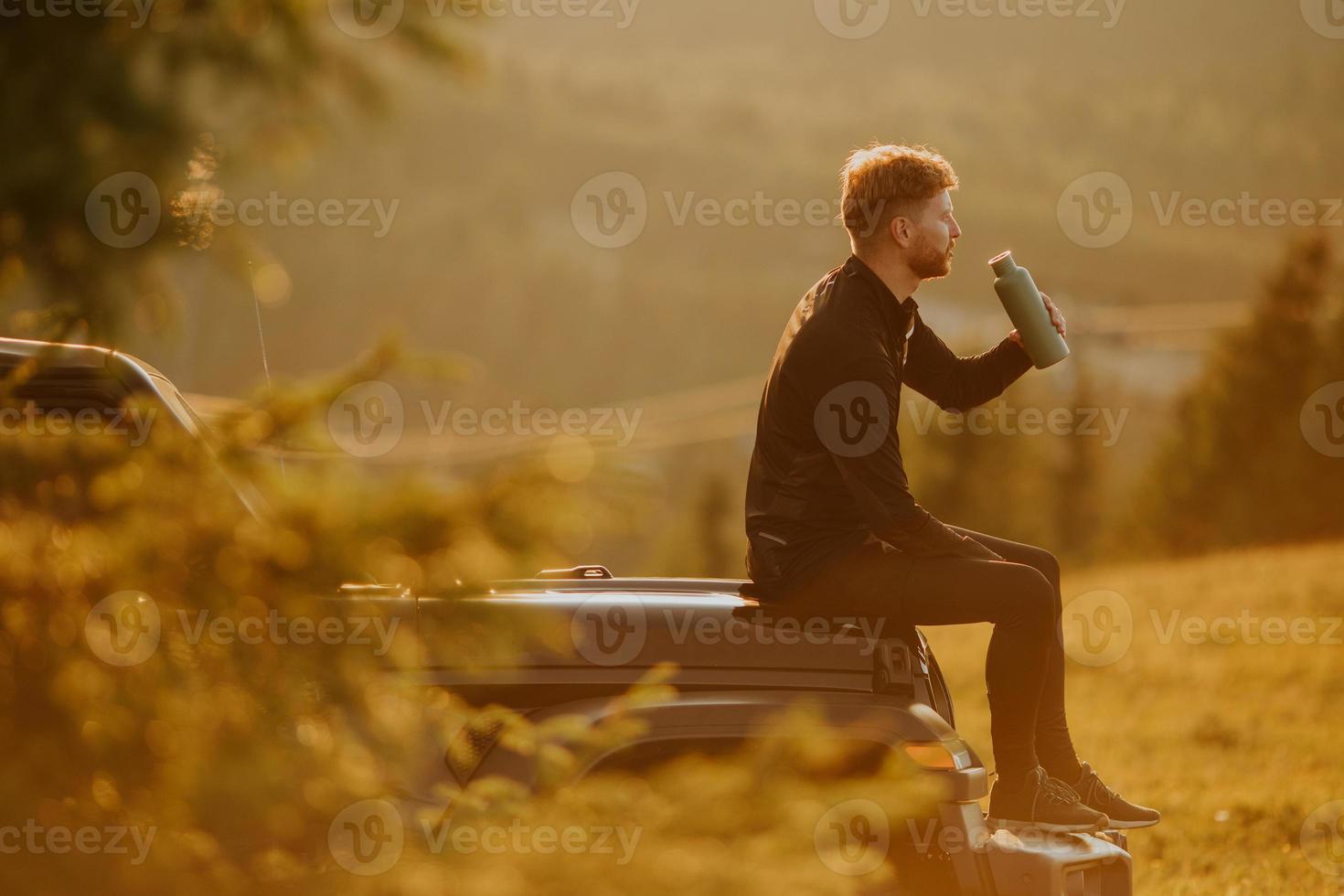 Young man relaxing on a terrain vehicle hood at countryside photo