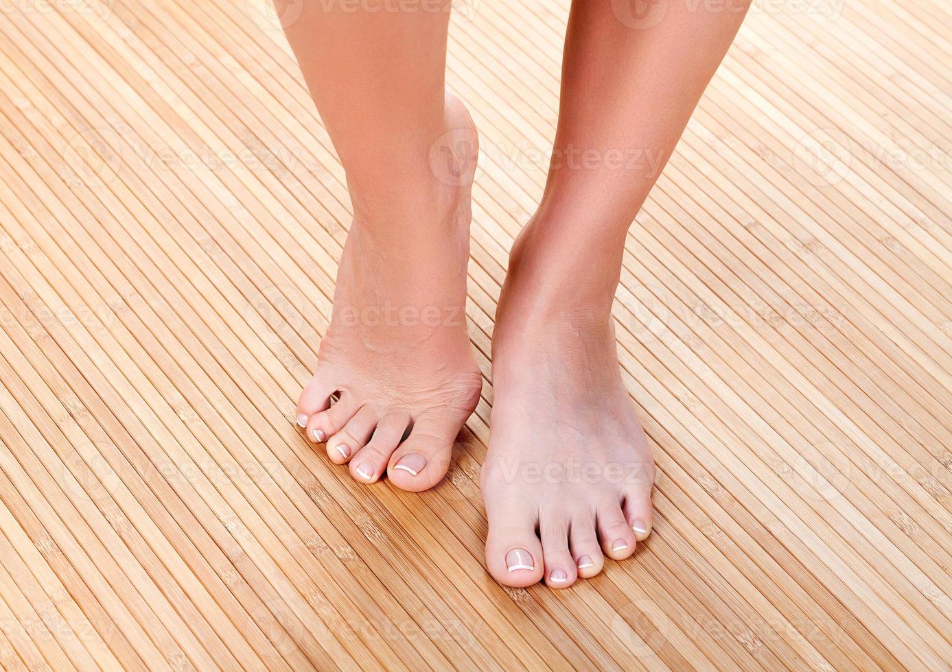 Beautiful female feet on a wooden floor, closeup shot photo