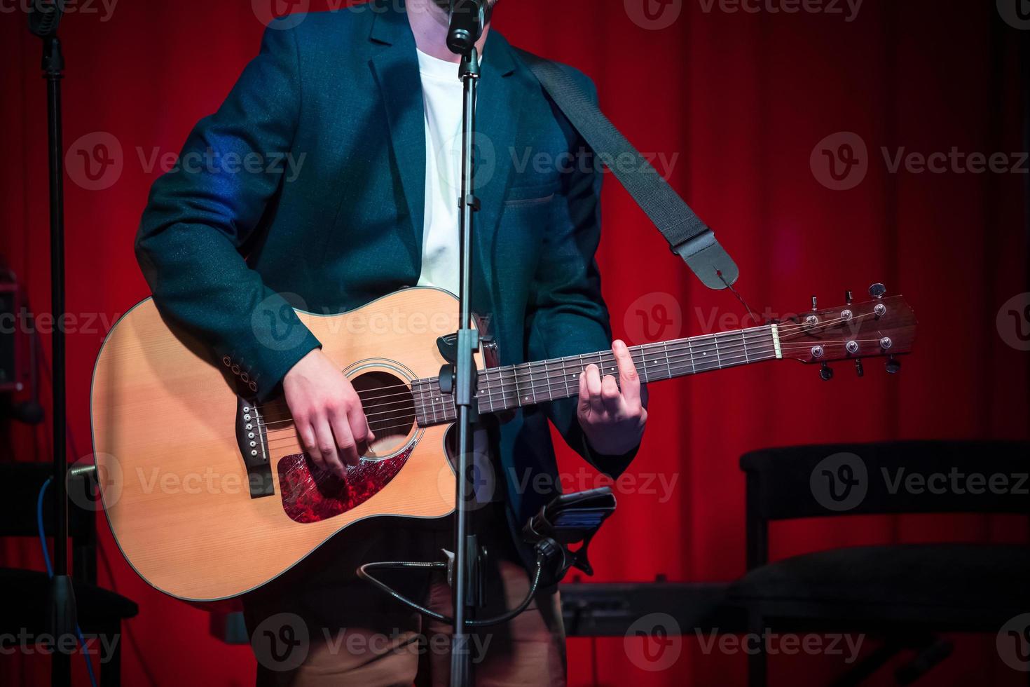 Man plays classical guitar against red curtain photo