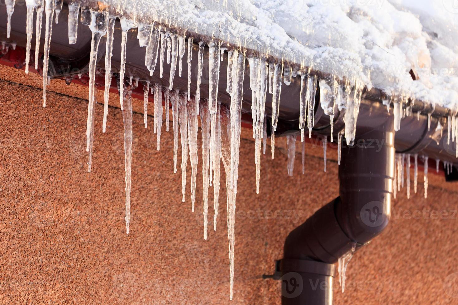 Winter icicles hanging from eaves of roof photo