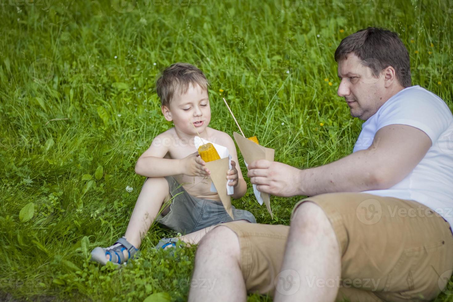 Eat corn in summer sitting on a green lawn. Summer, snack. photo