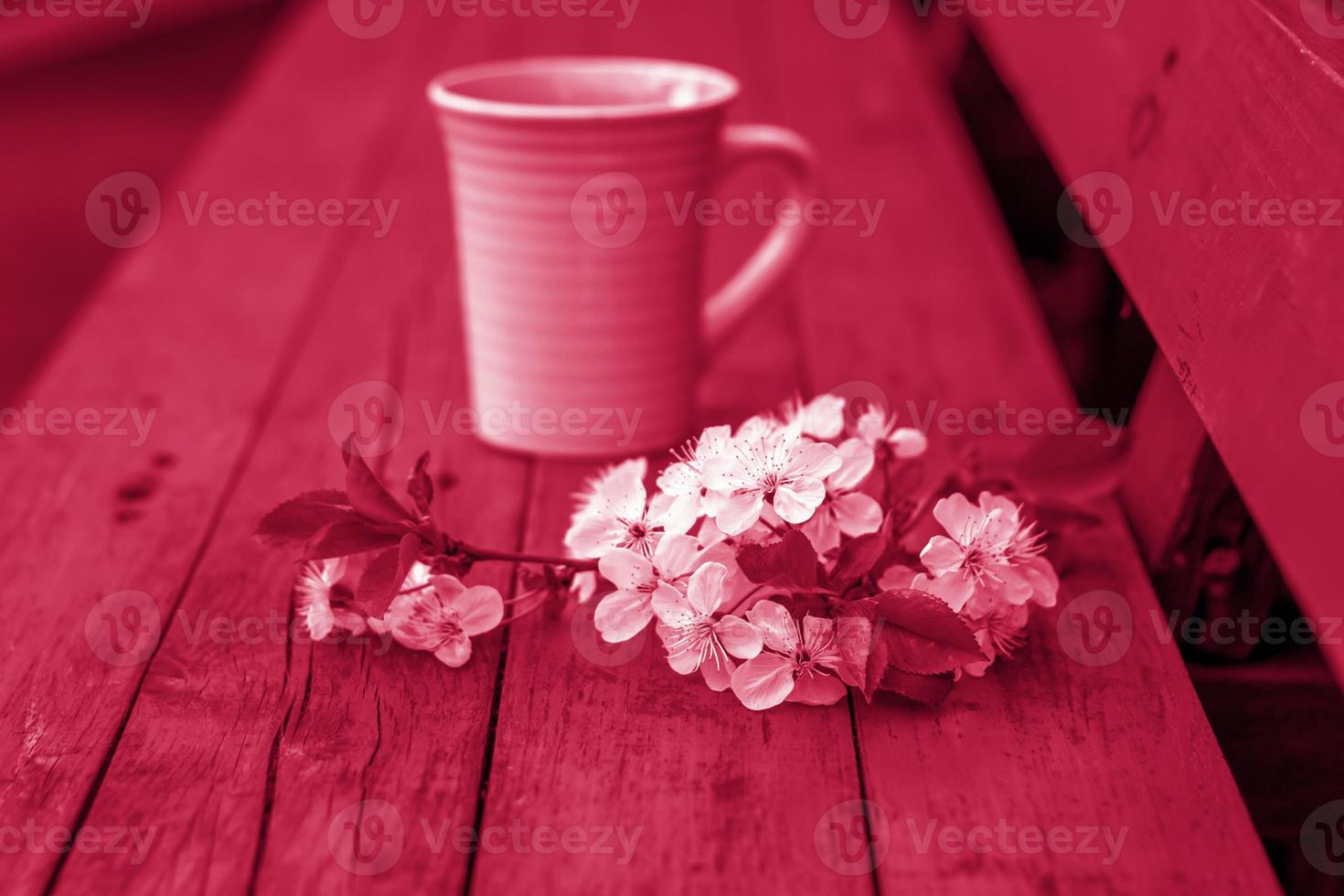 a cup of coffee on a dark, worn rustic wooden table. The composition is decorated with a twig with white flowers. Cherry tree flowers. Selective focus. photo