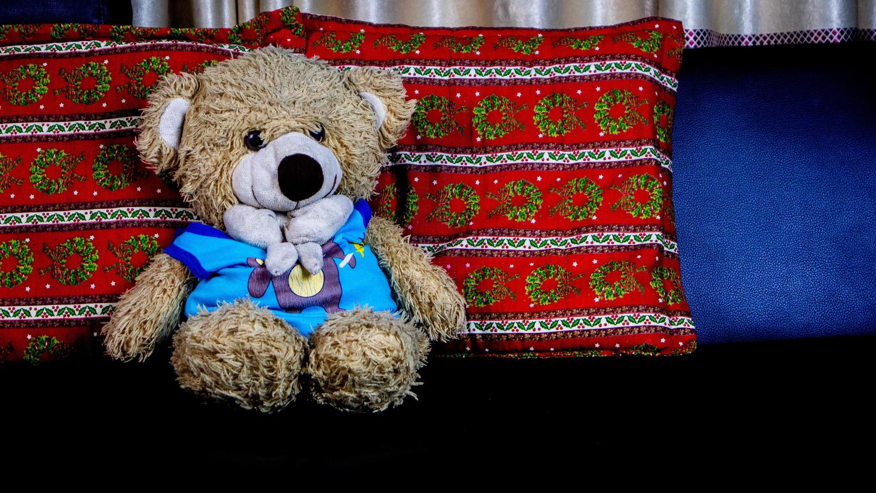 teddy bear in a blue t-shirt on a black sofa photo
