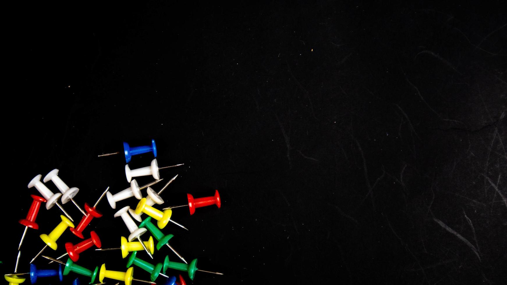 multicolored thumbtacks on a black background photo