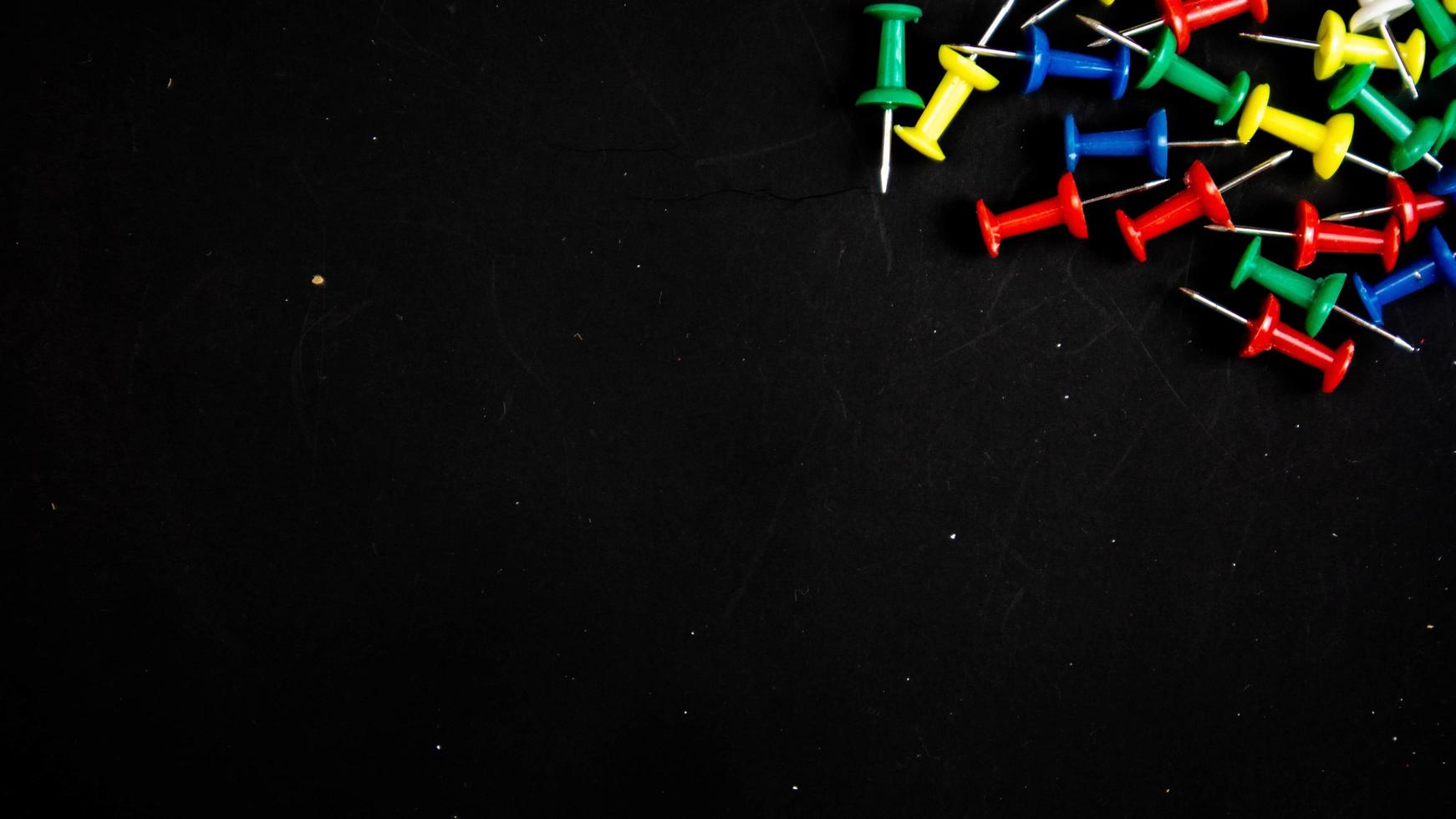 multicolored thumbtacks on a black background photo