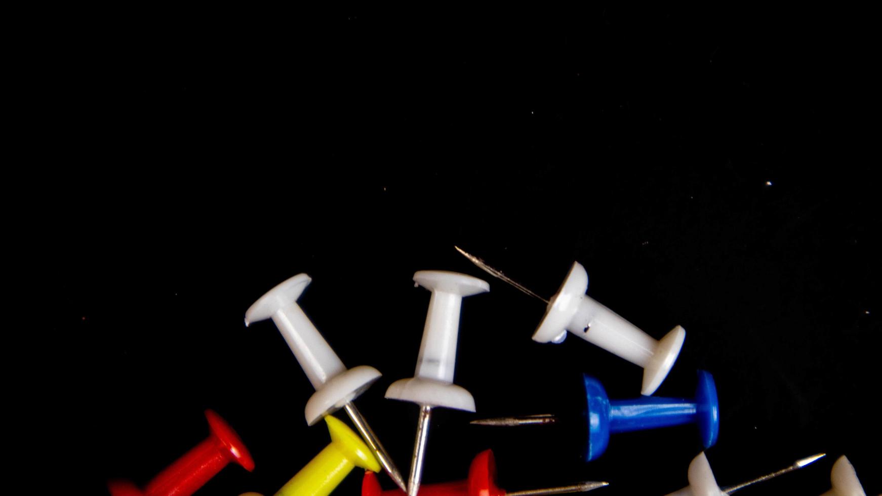 multicolored thumbtacks on a black background photo