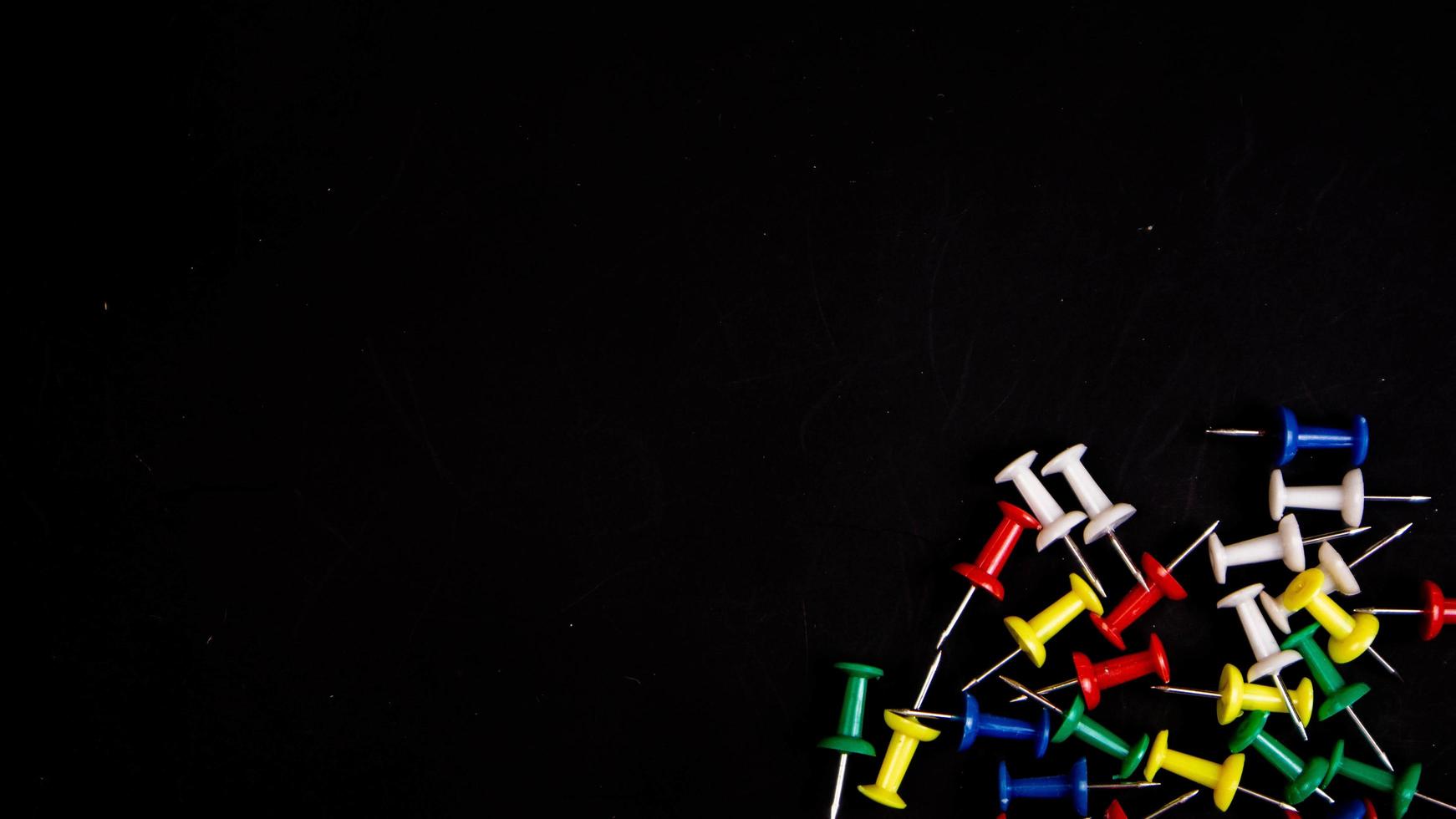 multicolored thumbtacks on a black background photo