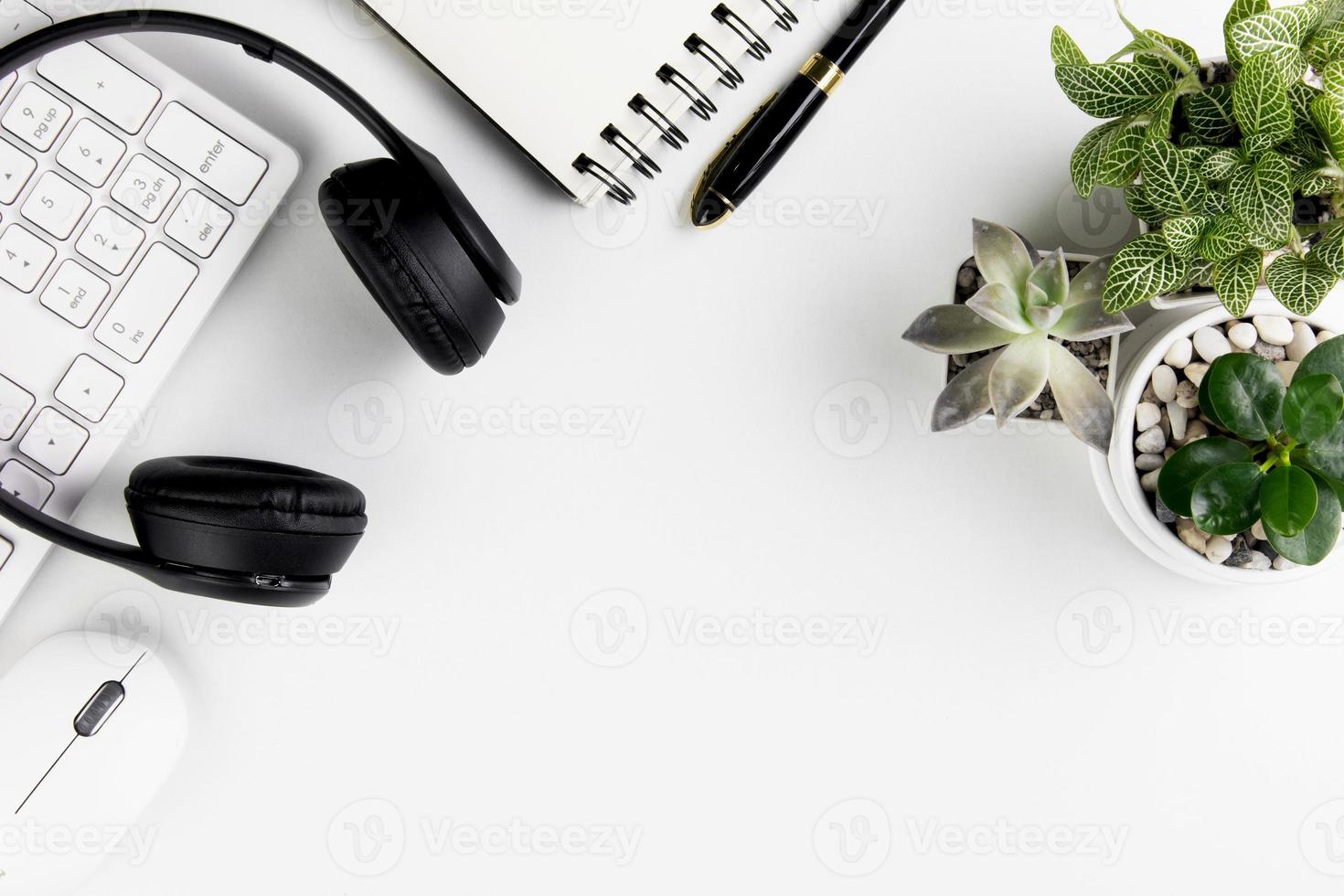 vista superior del escritorio de oficina blanco moderno con teclado de computadora, página de cuaderno en blanco y otros equipos sobre fondo blanco. concepto de espacio de trabajo, estilo de gestión del espacio de trabajo, espacio de diseño empresarial con copia foto