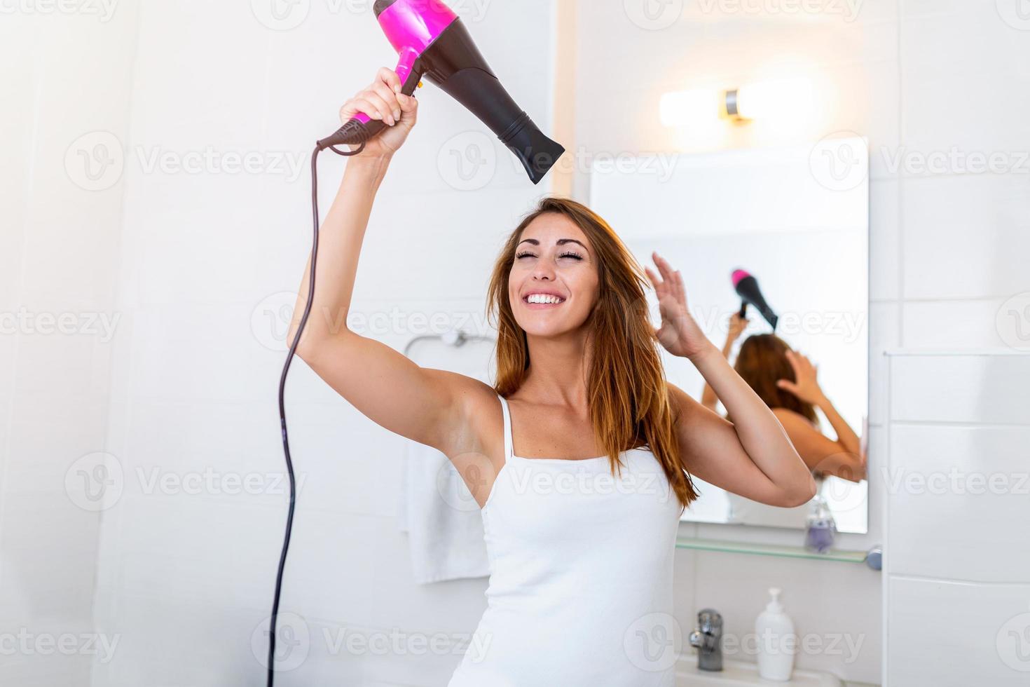 cuidado del cabello. mujer secando hermoso cabello largo y recto con secador. retrato de chica atractiva con secador de pelo. concepto de peinado. alta resolución foto