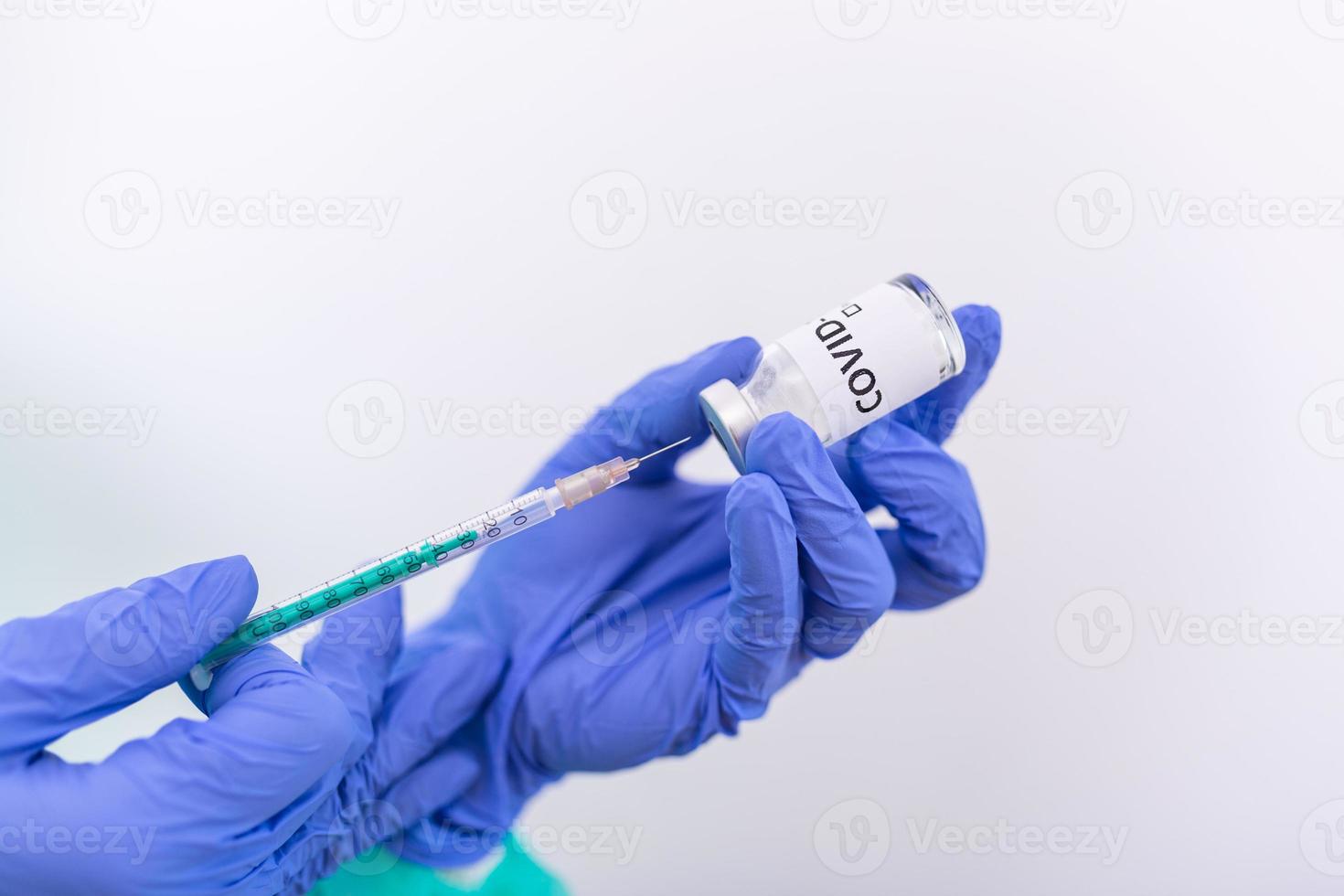 Doctor, nurse or scientist hand in blue nitrile gloves holding flu, measles, coronavirus COVID-19 vaccine shot for baby and adult vaccination, medicine and drug concept photo