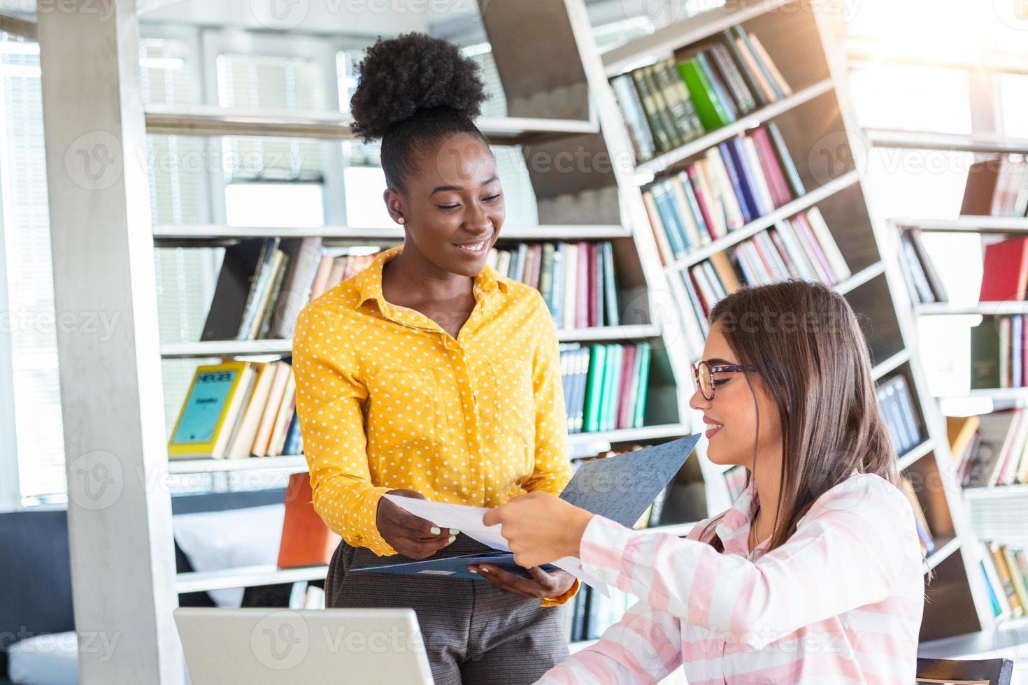 Working team is talking at desk with laptop in modern office. Two people discussing information seen on screen of silvery device and smiling friendly. Prospective staff dressed in formal clothes photo
