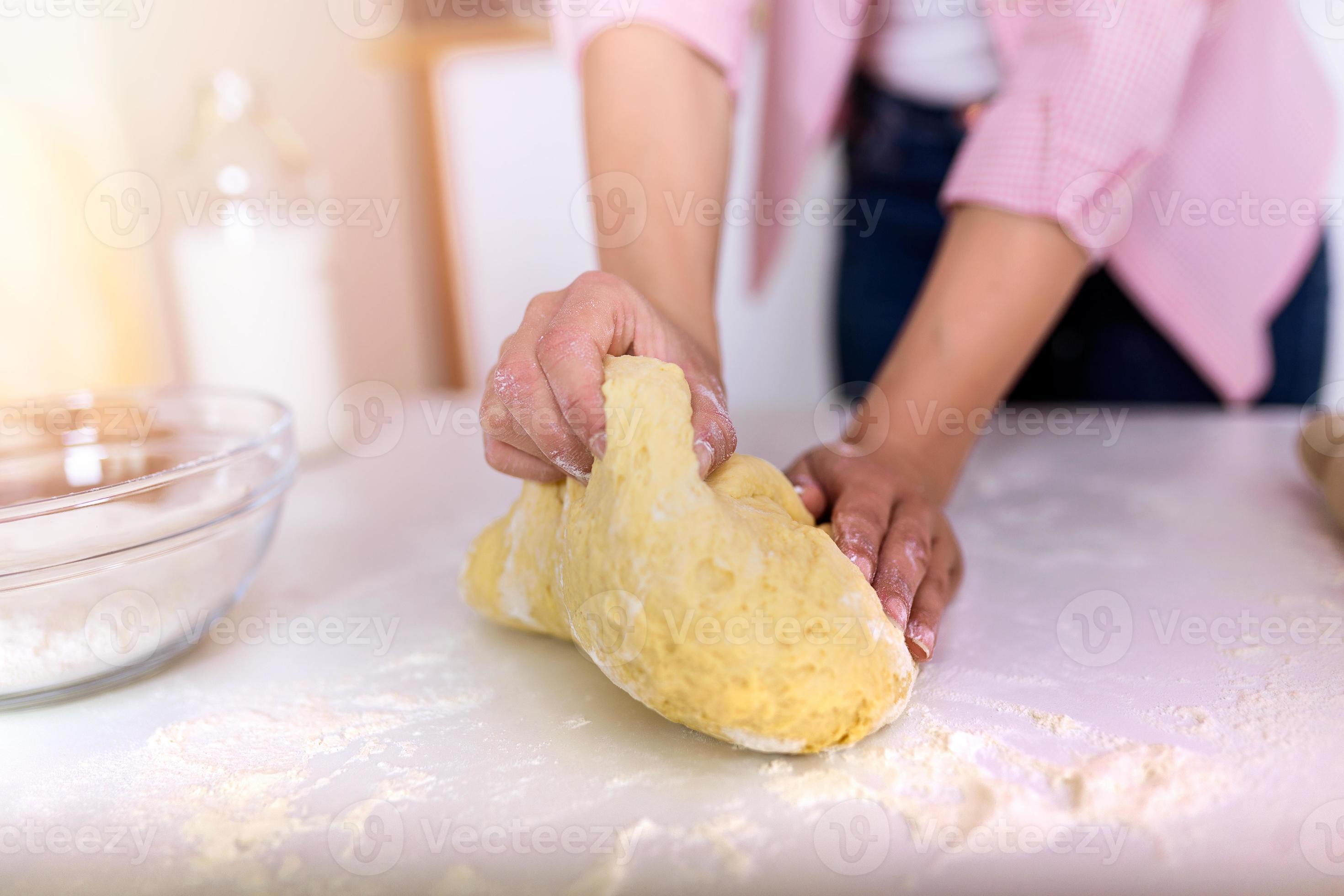 Close up of female baker hands kneading dough and making bread. cooking