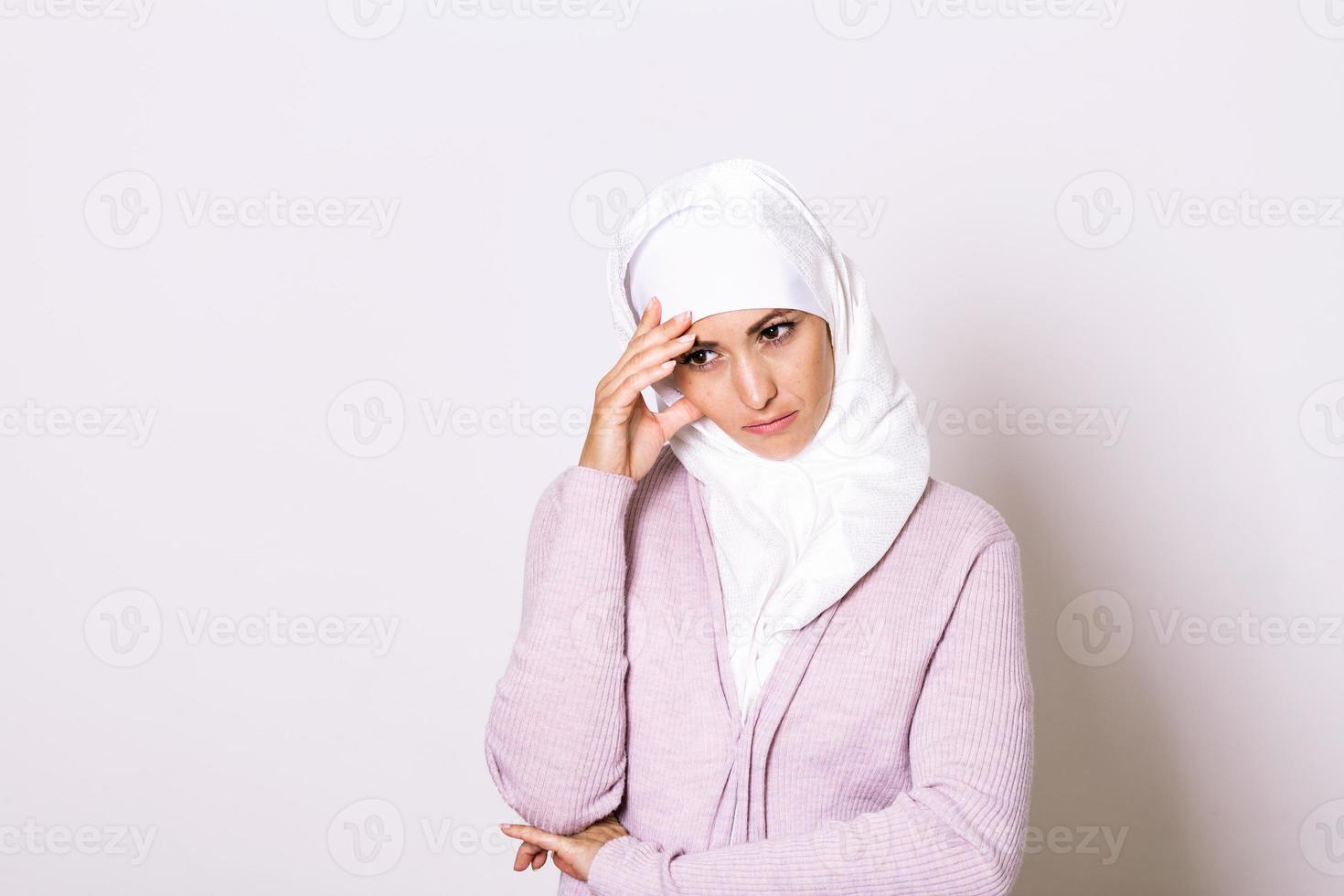 Arab saudi emirates woman with head ache. Portrait of unhappy young woman with bad headache. Portrait of beautiful young muslim woman with bare shoulders touching her temples feeling stress photo