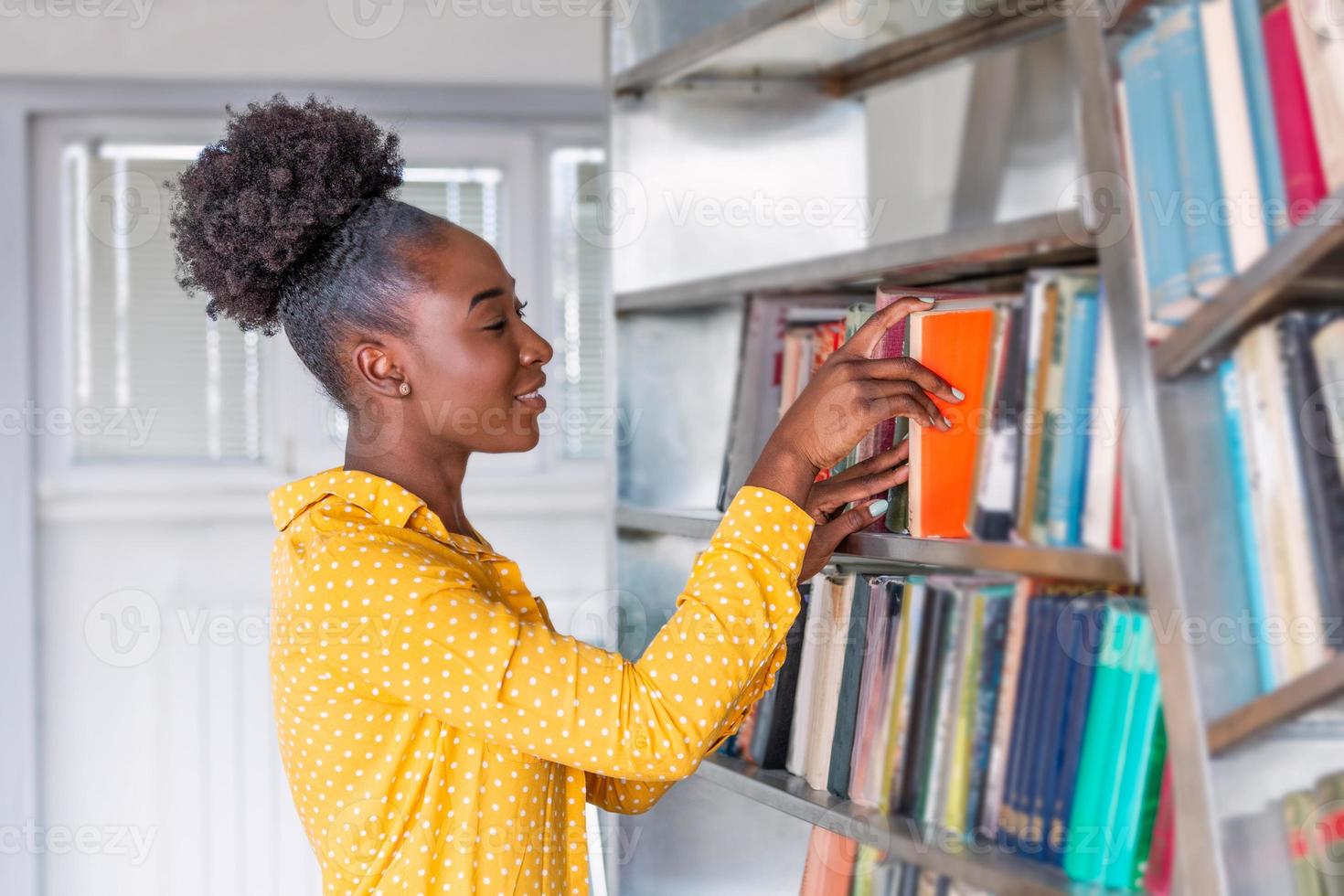 mujer tomando un libro de la estantería de la biblioteca. joven bibliotecario buscando libros y tomando un libro de la estantería de la biblioteca foto