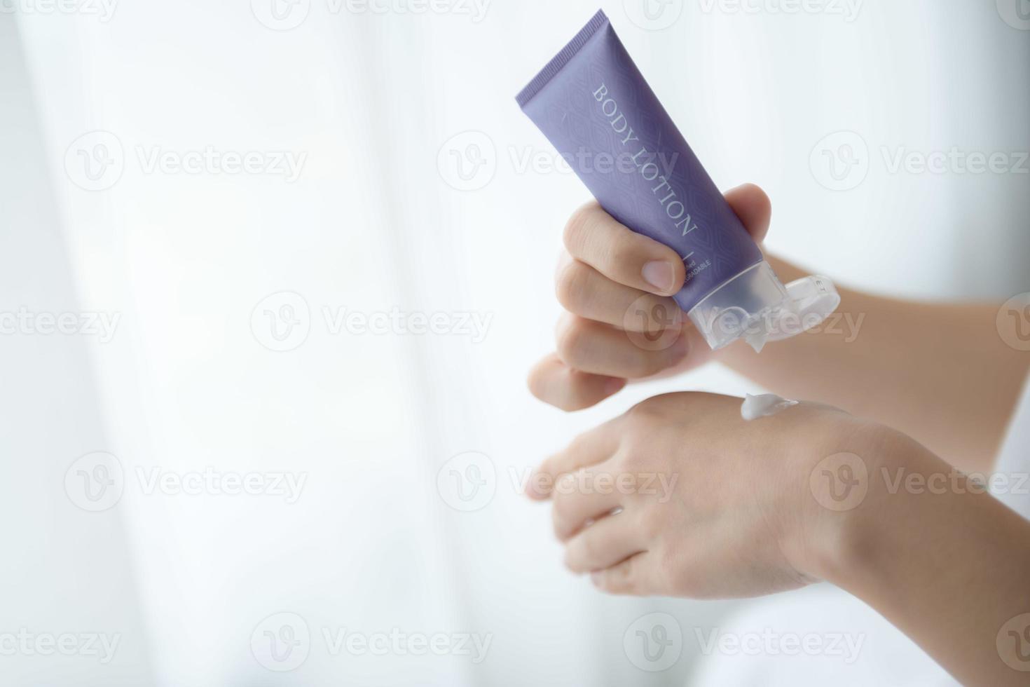 primer plano de mujeres que aplican crema de loción corporal en la mano. foto