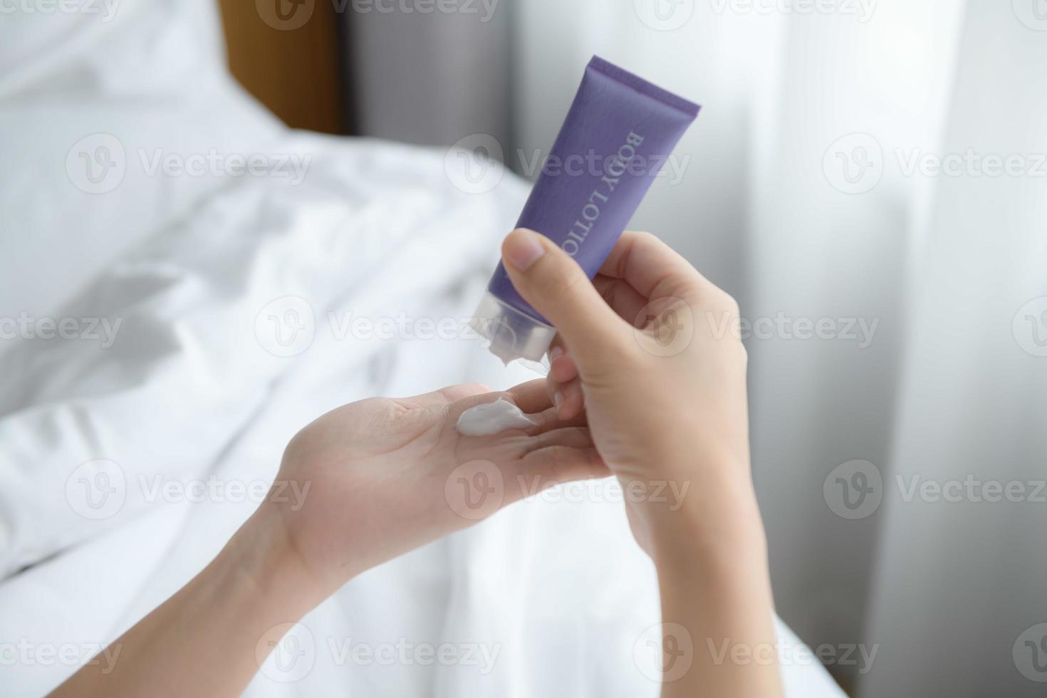 Close up of women applying body lotion cream on hand. photo