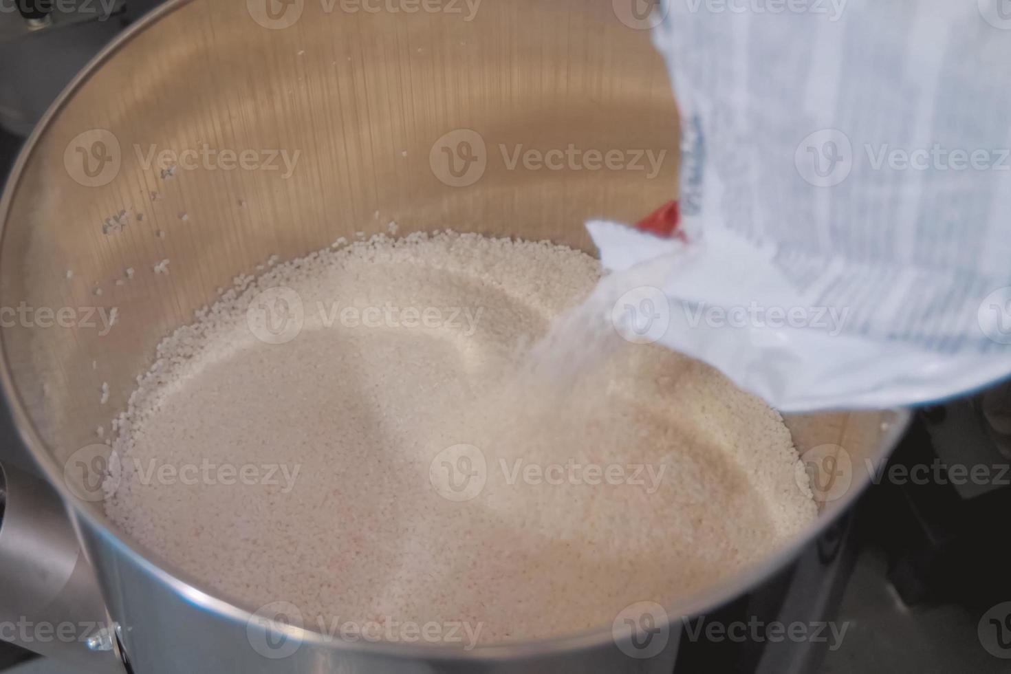 Pouring polymer granules into steel tank. Making explosives. photo