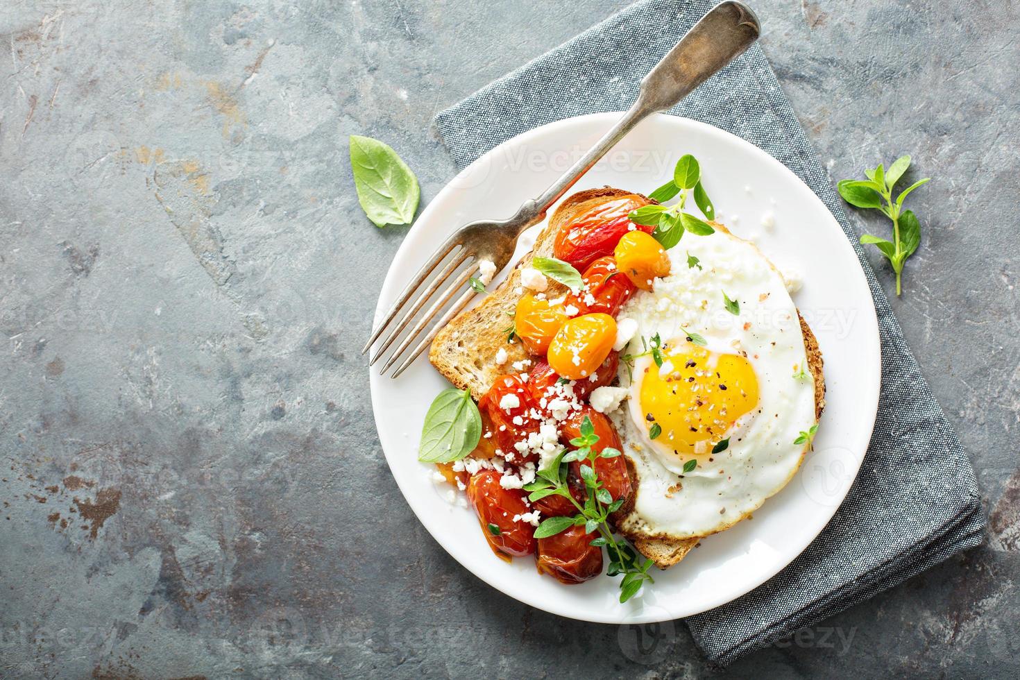 Multigrain toast with fried egg and roasted tomatoes photo