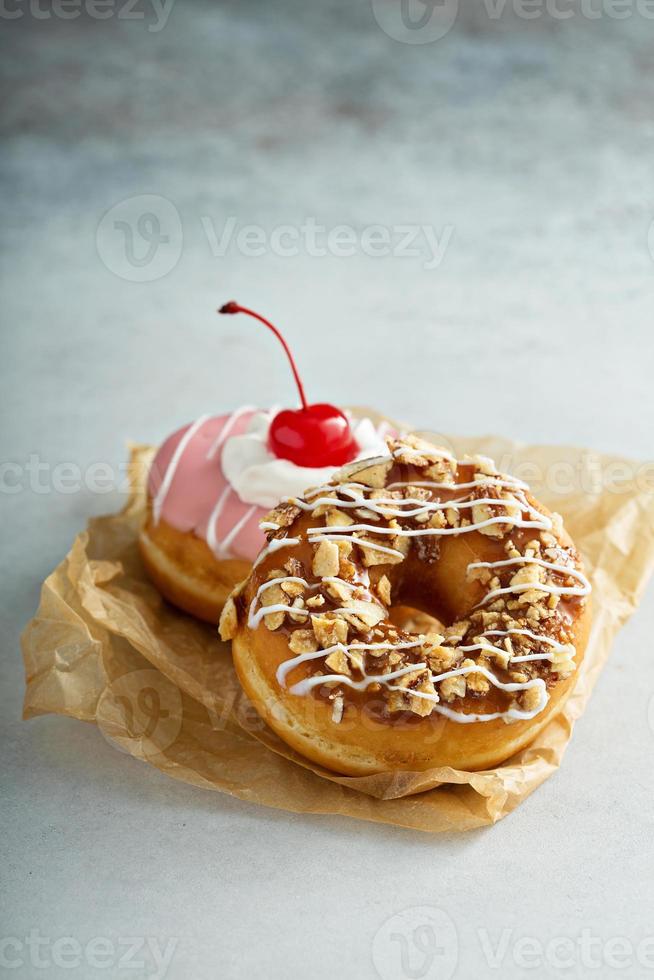 Assorted glazed fried donuts on parchment photo