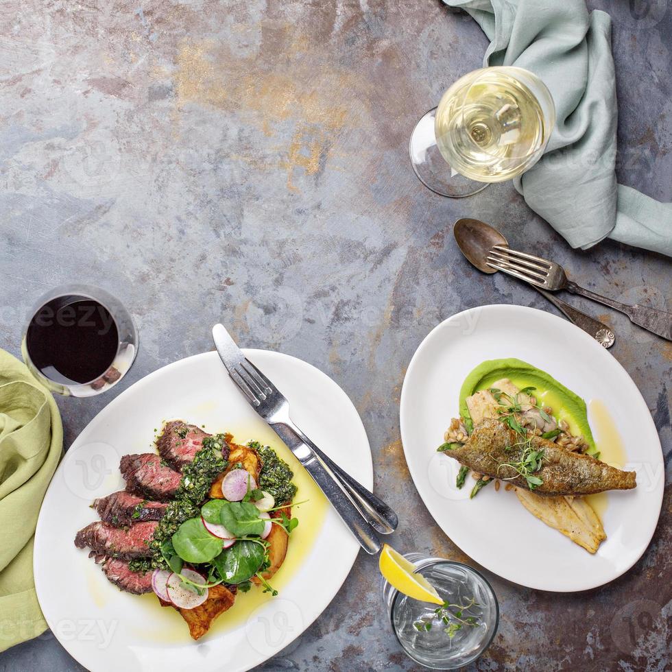 Big dinner table overhead view with steak and fish photo