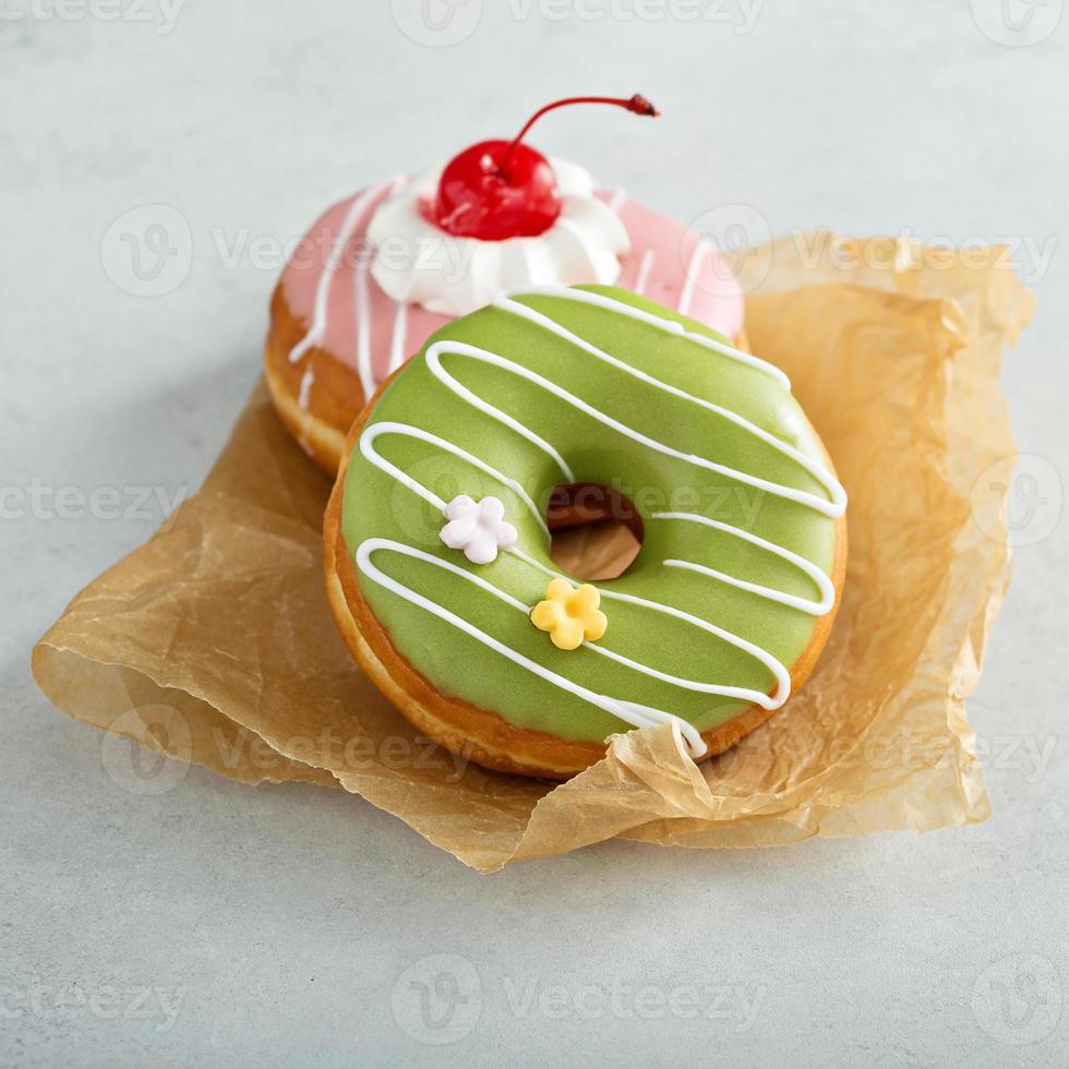 Assorted glazed fried donuts on parchment photo