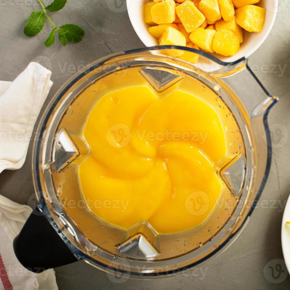 Making smoothie with frozen mango photo