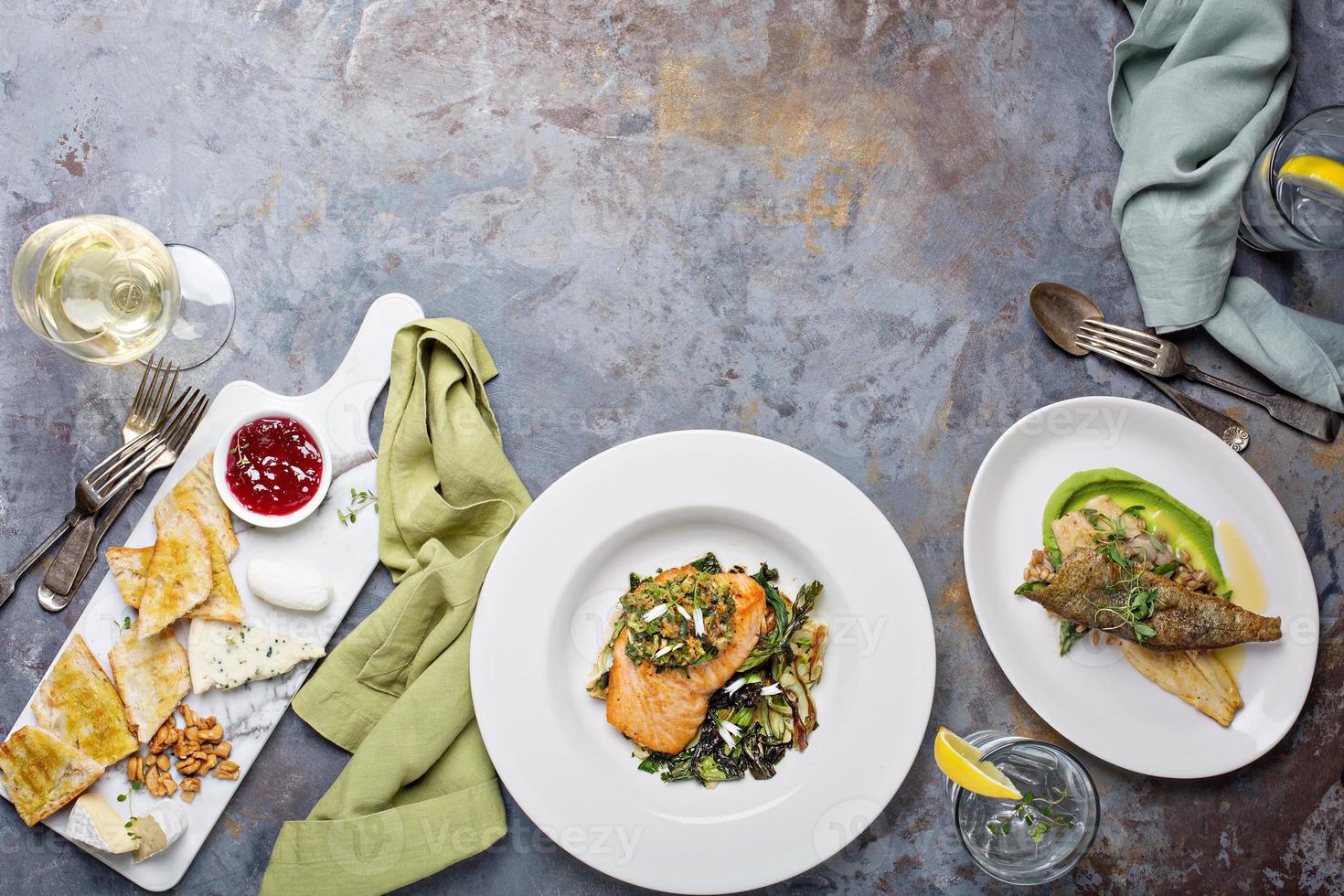 Big dinner table overhead view with steak and fish photo